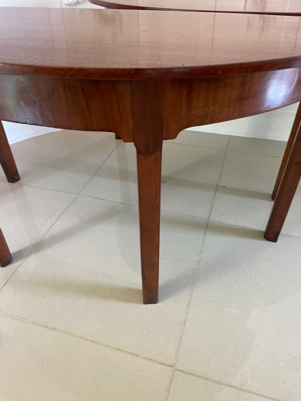 A pair of George III mahogany demi-lune console tables with polished semi-circular tops and straight tapered legs. View II
