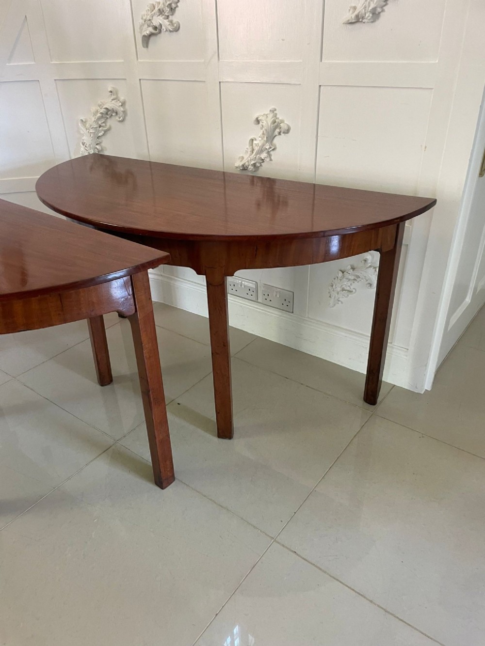 A pair of George III mahogany demi-lune console tables with polished semi-circular tops and straight tapered legs. View V