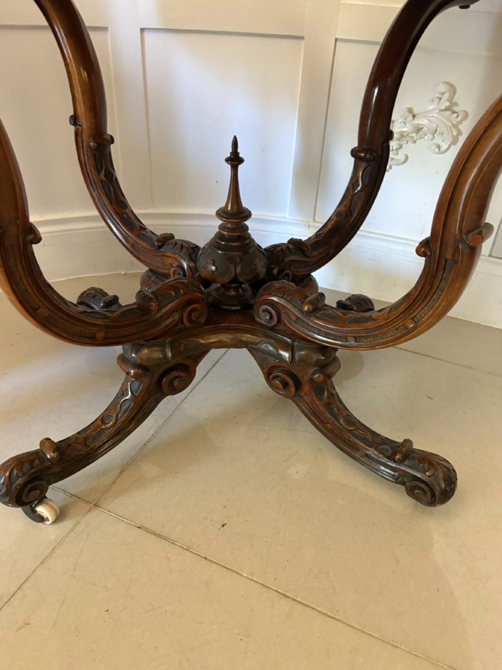 A Victorian burr walnut centre table featuring a shaped top, carved scroll frieze, and an elaborate four-legged base with a central turned finial. View VIII