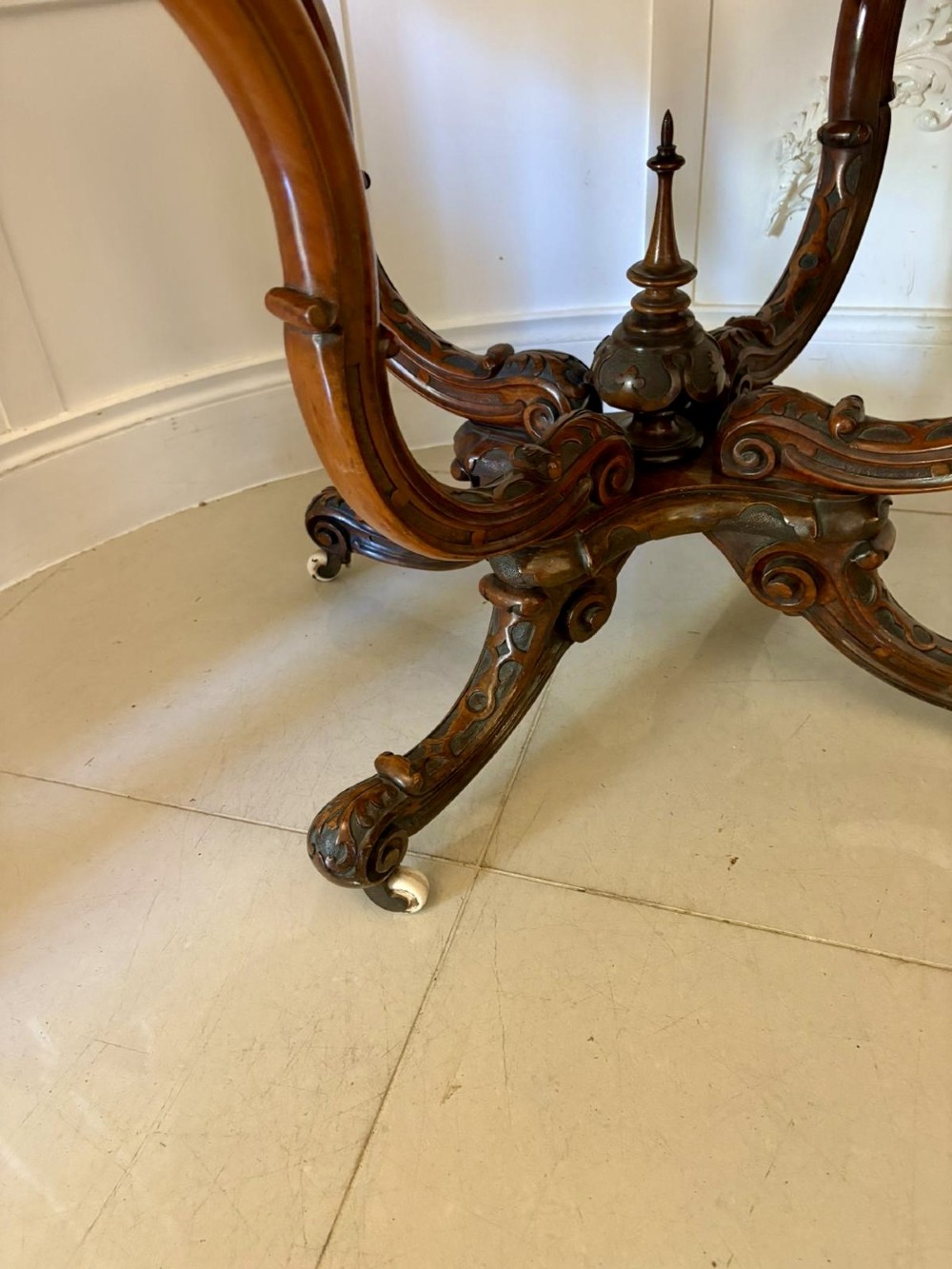 A Victorian burr walnut centre table featuring a shaped top, carved scroll frieze, and an elaborate four-legged base with a central turned finial. View IX