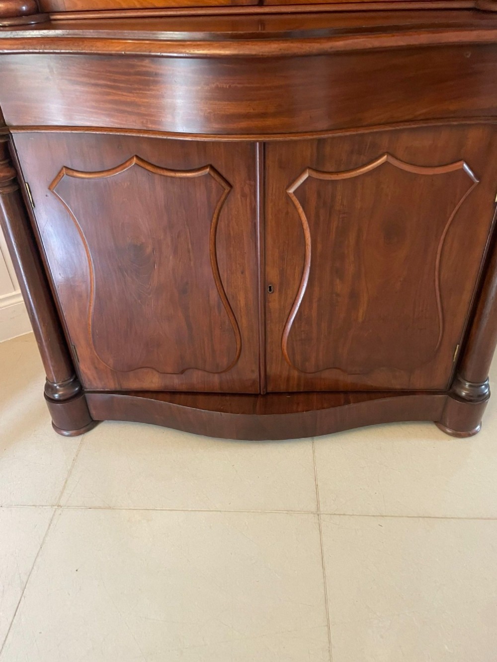 A Victorian mahogany glazed bookcase featuring two upper arched glass doors flanked by turned columns above a curved two-door cupboard base. View III