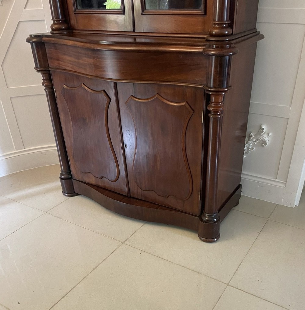 A Victorian mahogany glazed bookcase featuring two upper arched glass doors flanked by turned columns above a curved two-door cupboard base. View IV