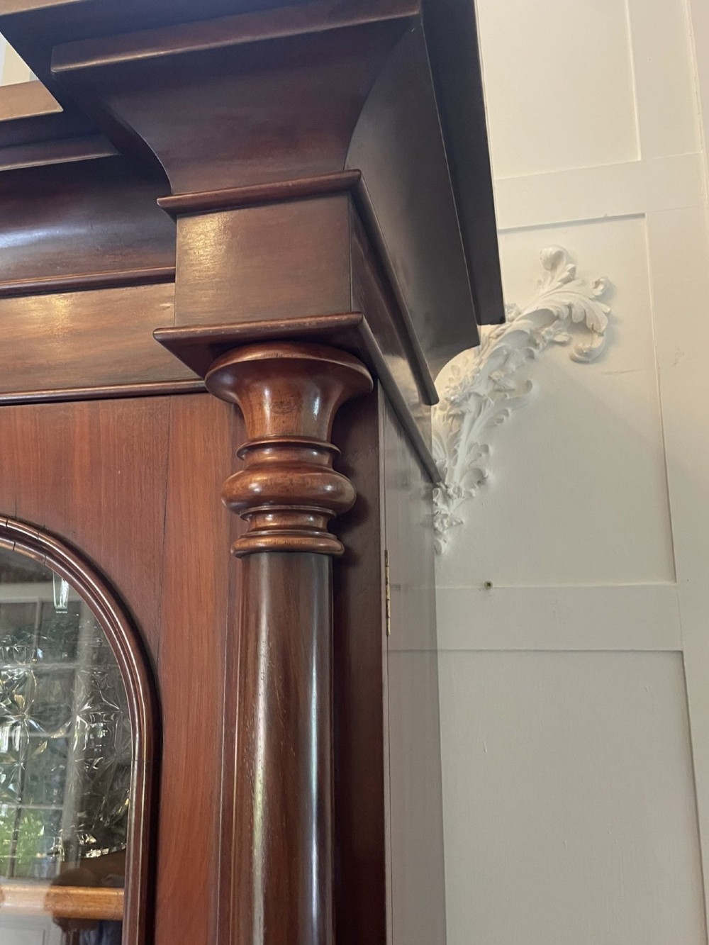 A Victorian mahogany glazed bookcase featuring two upper arched glass doors flanked by turned columns above a curved two-door cupboard base. View VII