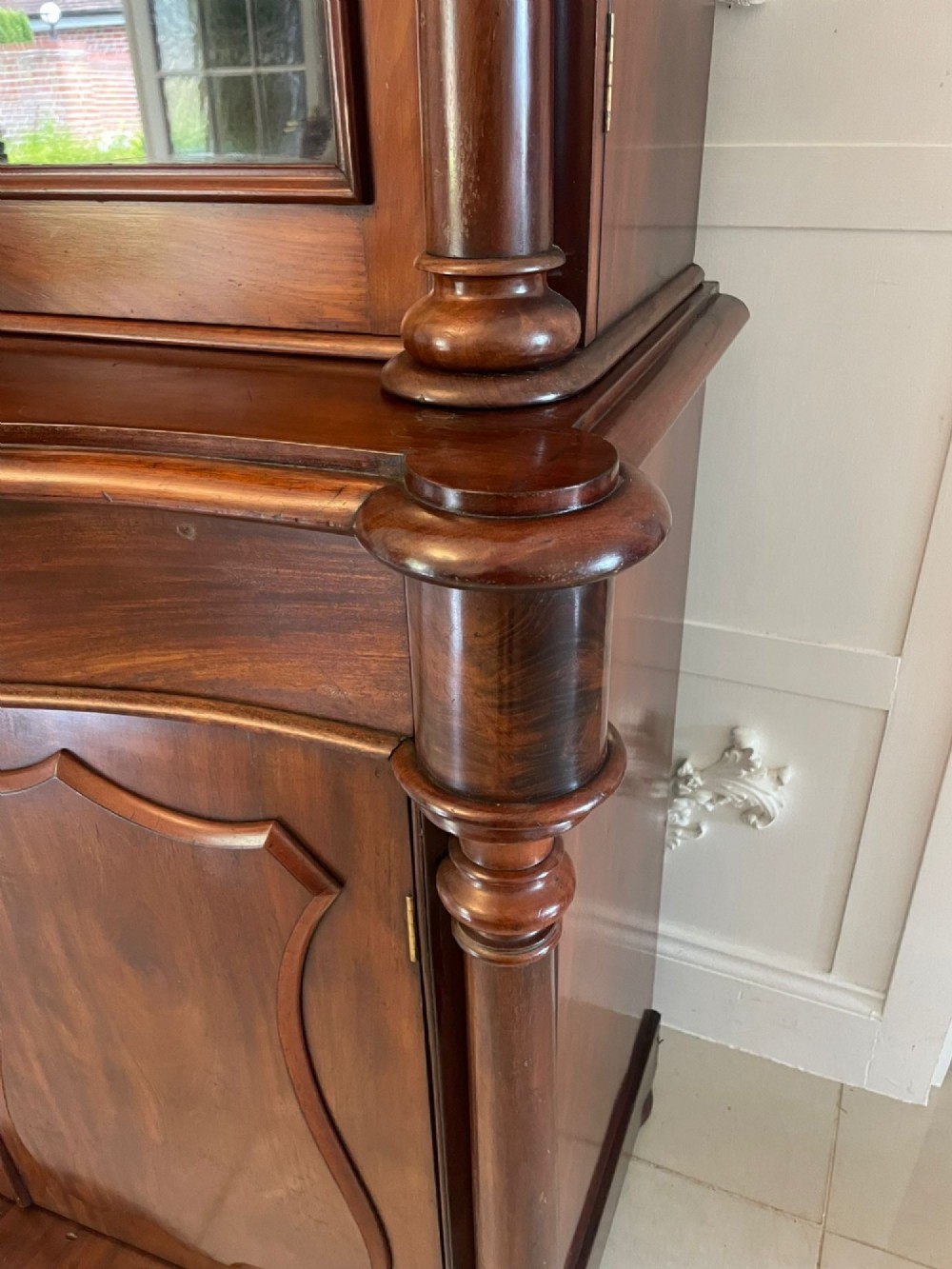 A Victorian mahogany glazed bookcase featuring two upper arched glass doors flanked by turned columns above a curved two-door cupboard base. View VIII