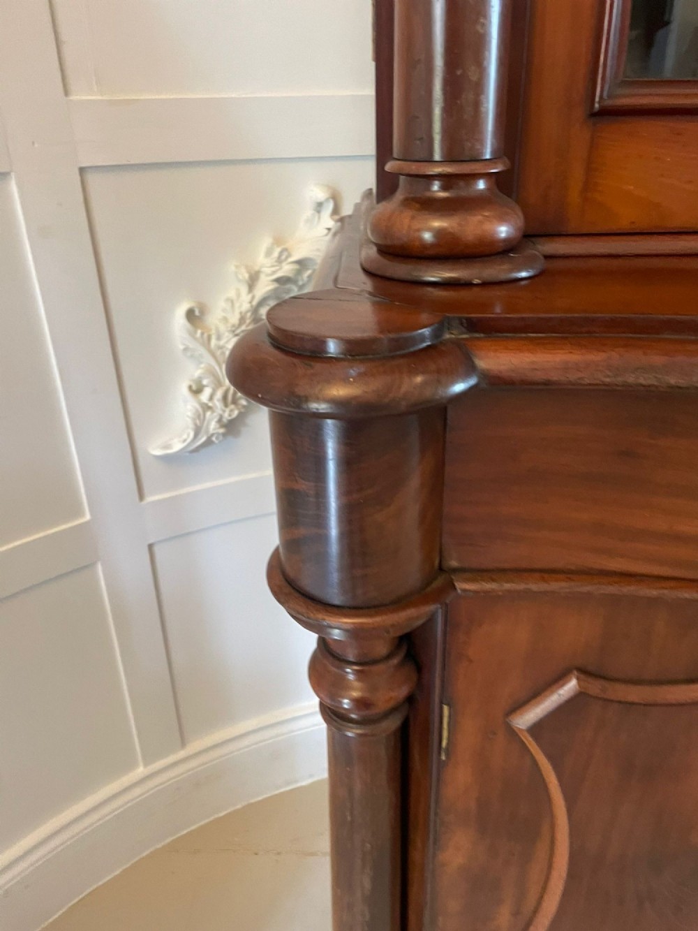 A Victorian mahogany glazed bookcase featuring two upper arched glass doors flanked by turned columns above a curved two-door cupboard base. View IX