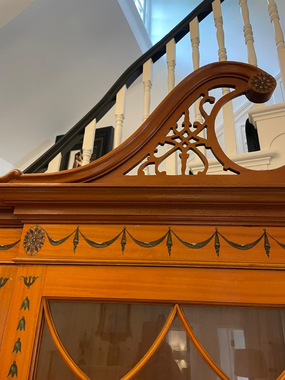 A large satinwood breakfront display cabinet featuring a swan-neck pediment, astragal glazed upper doors, and painted neoclassical motifs. View XI