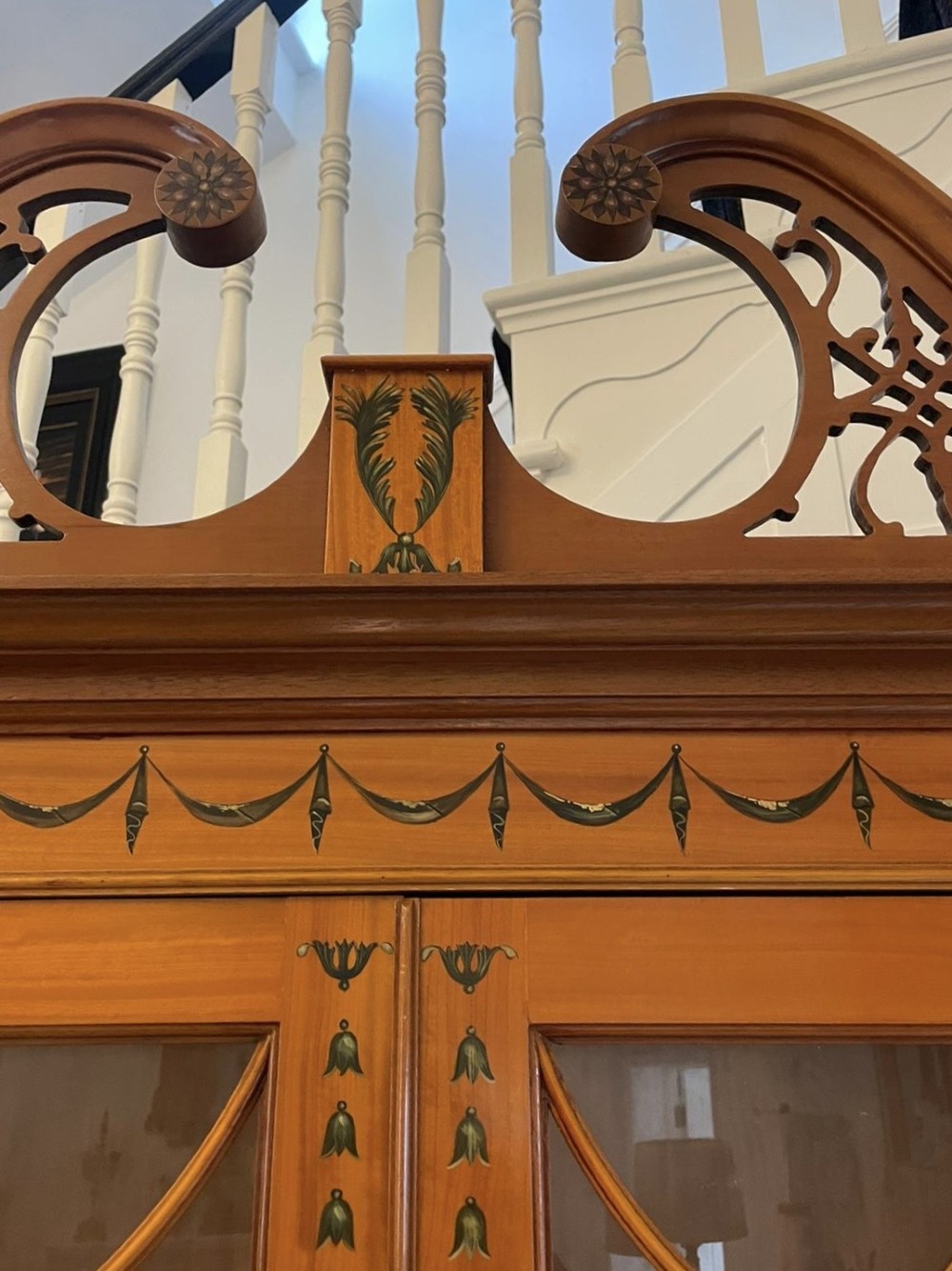 A large satinwood breakfront display cabinet featuring a swan-neck pediment, astragal glazed upper doors, and painted neoclassical motifs. View XIV