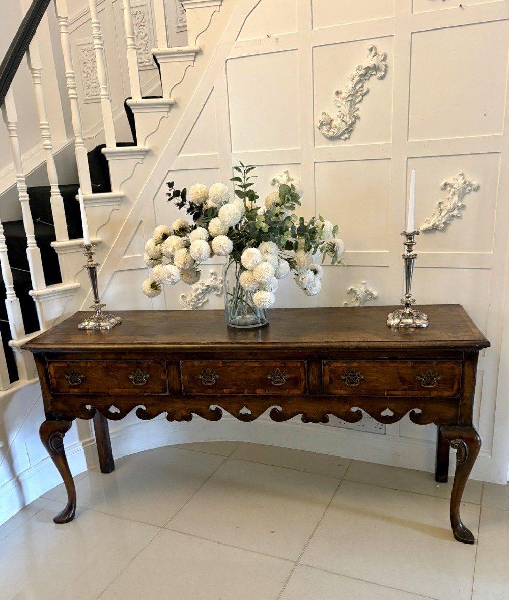A dark brown oak Georgian style dresser base featuring three drawers with brass drop handles, a decorative scalloped apron, and front cabriole legs. View II