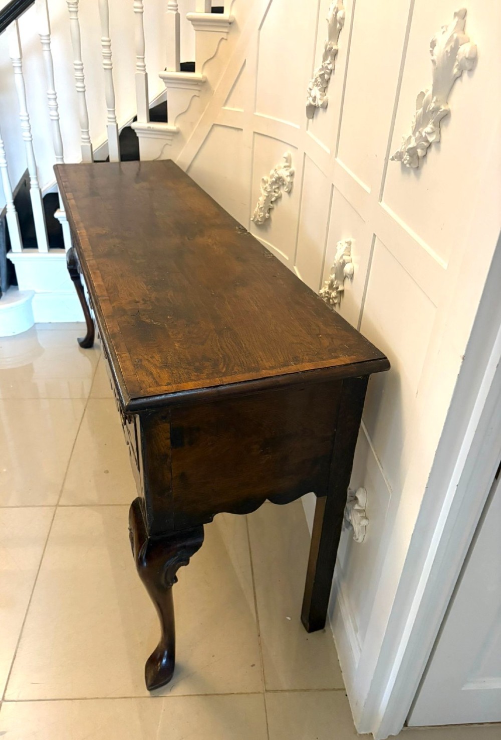 A dark brown oak Georgian style dresser base featuring three drawers with brass drop handles, a decorative scalloped apron, and front cabriole legs. View VII