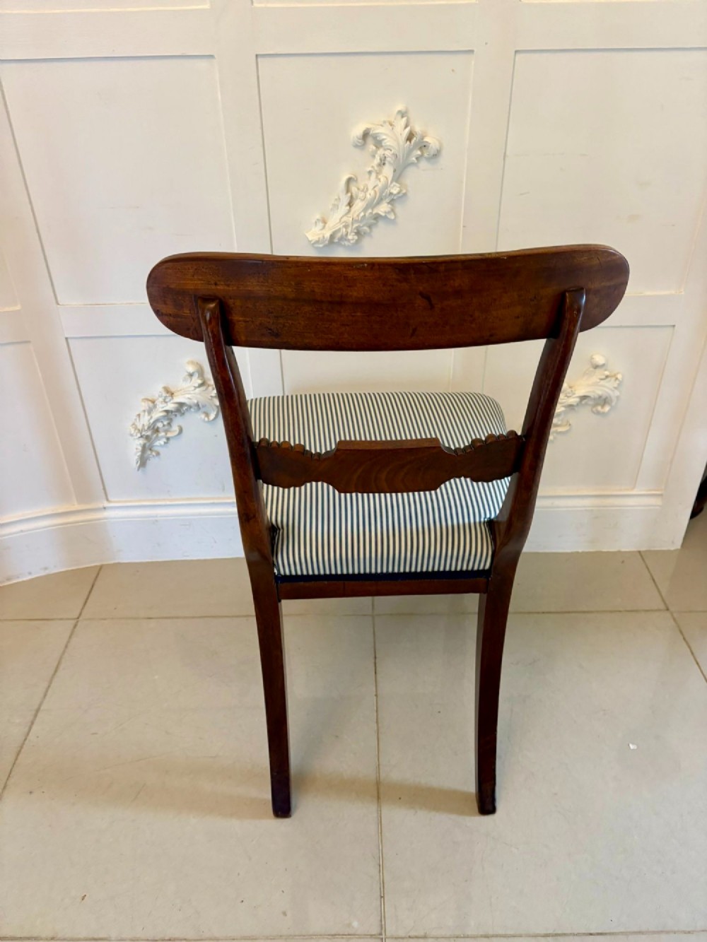 A set of four antique Regency mahogany dining chairs with carved top rails, reeded turned front legs, and blue and white striped upholstered seats. View III