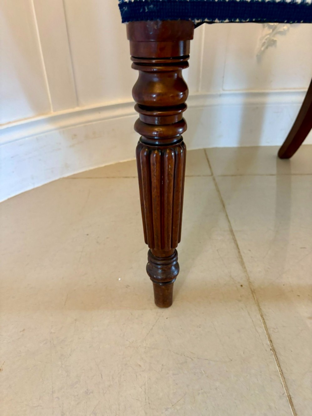 A set of four antique Regency mahogany dining chairs with carved top rails, reeded turned front legs, and blue and white striped upholstered seats. View VI