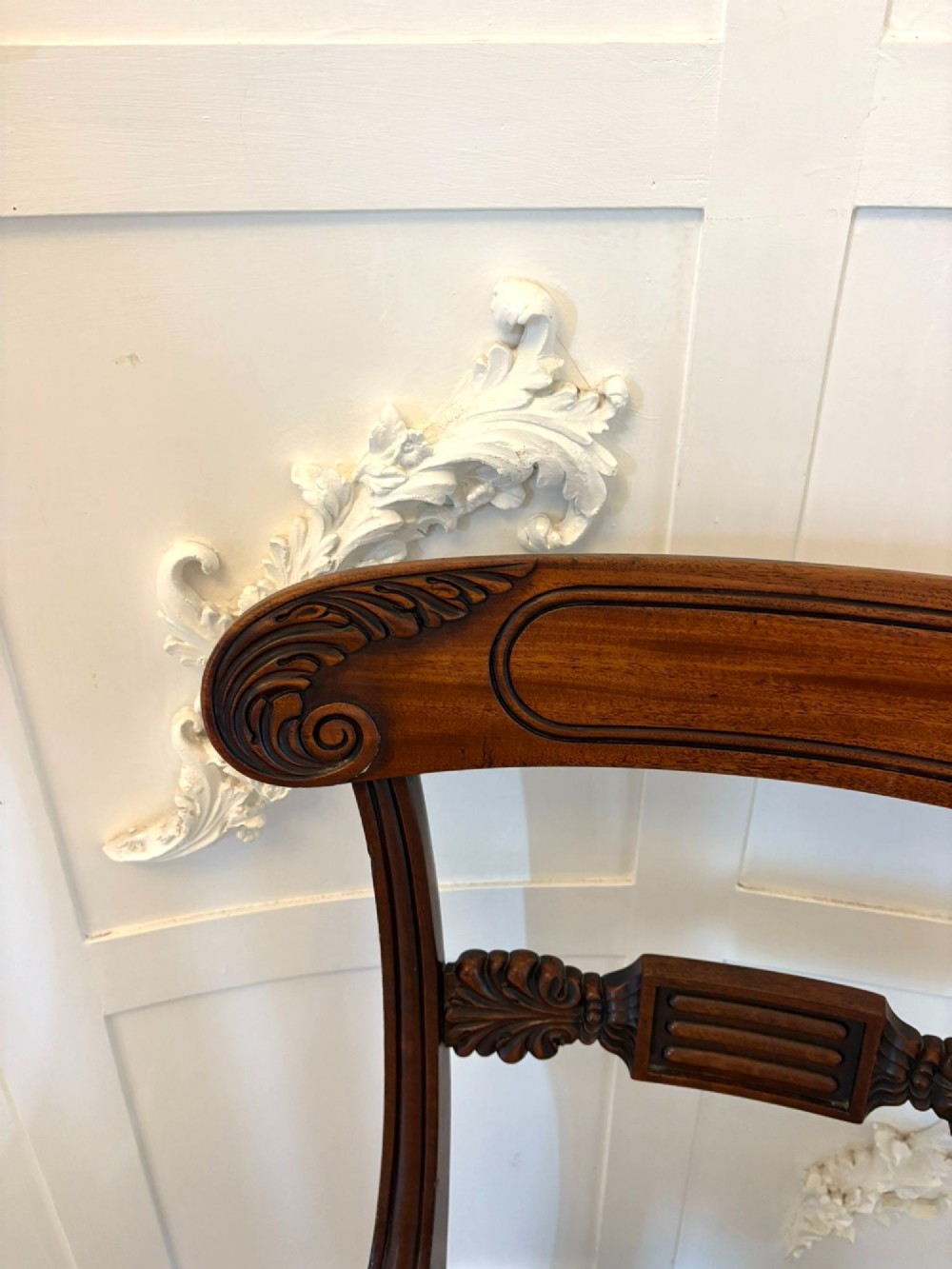 A set of four antique Regency mahogany dining chairs with carved top rails, reeded turned front legs, and blue and white striped upholstered seats. View VII