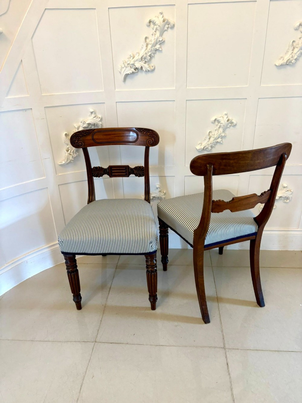 A set of four antique Regency mahogany dining chairs with carved top rails, reeded turned front legs, and blue and white striped upholstered seats. View VIII