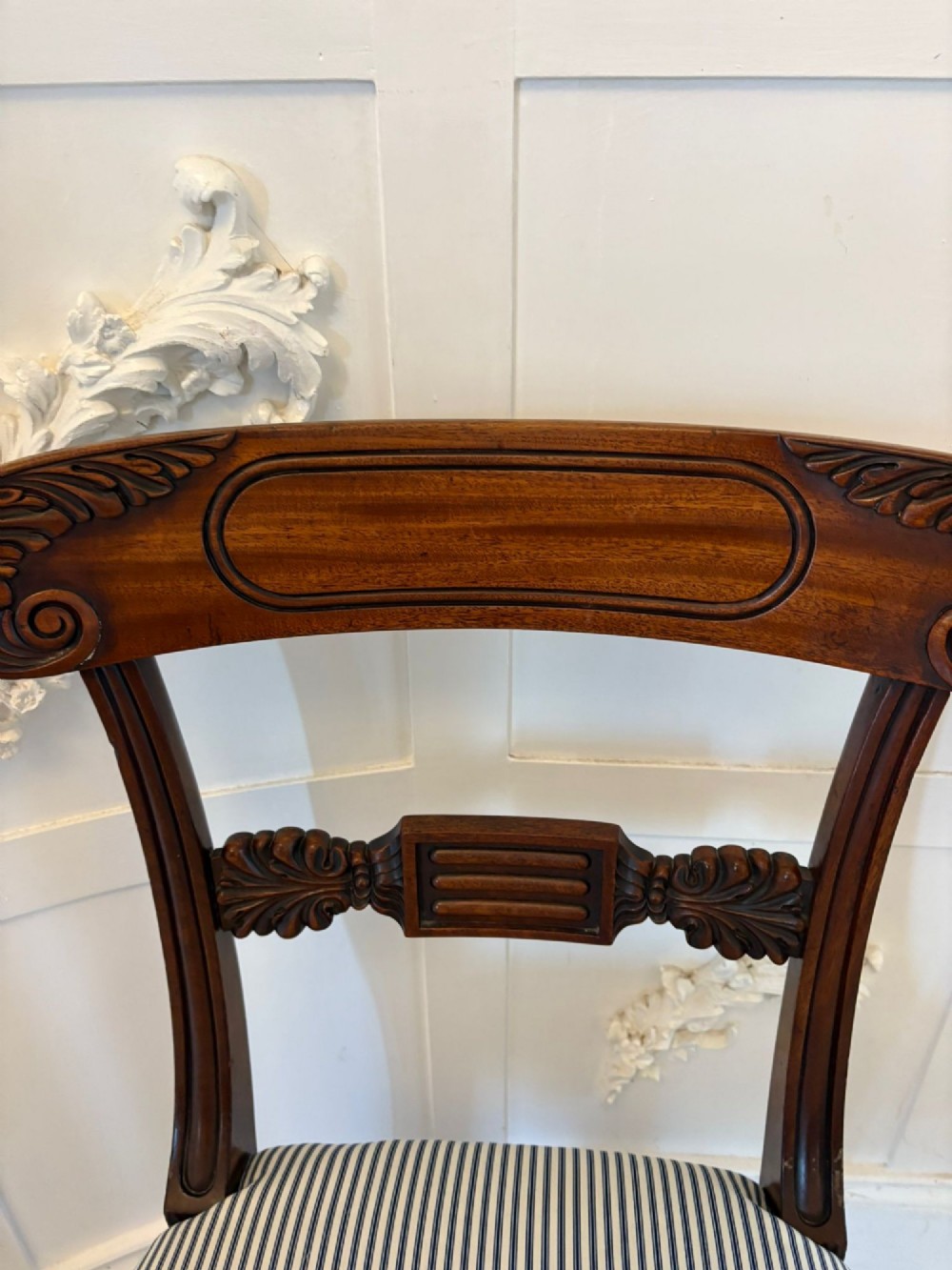 A set of four antique Regency mahogany dining chairs with carved top rails, reeded turned front legs, and blue and white striped upholstered seats. View IX