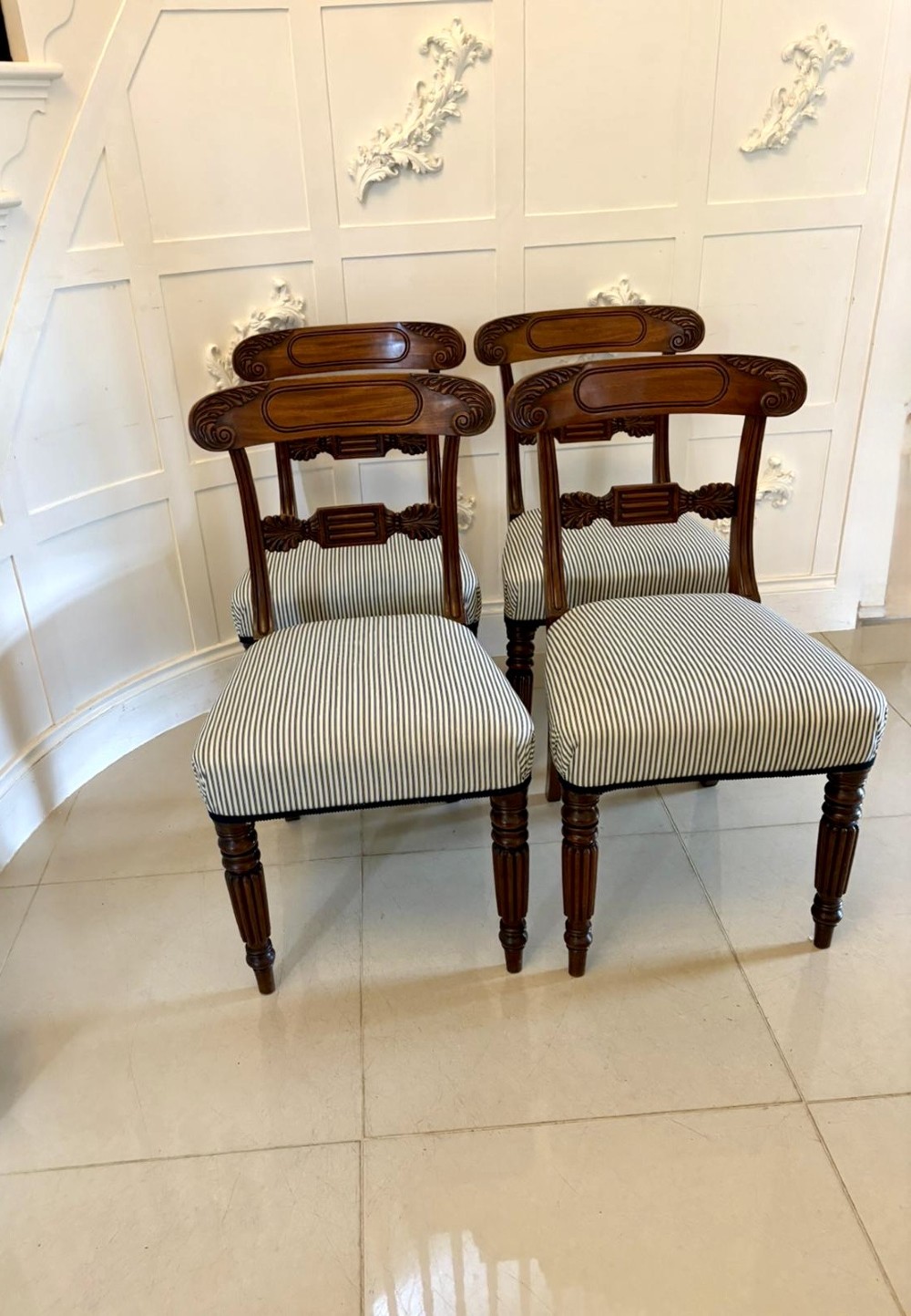 A set of four antique Regency mahogany dining chairs with carved top rails, reeded turned front legs, and blue and white striped upholstered seats. View XII