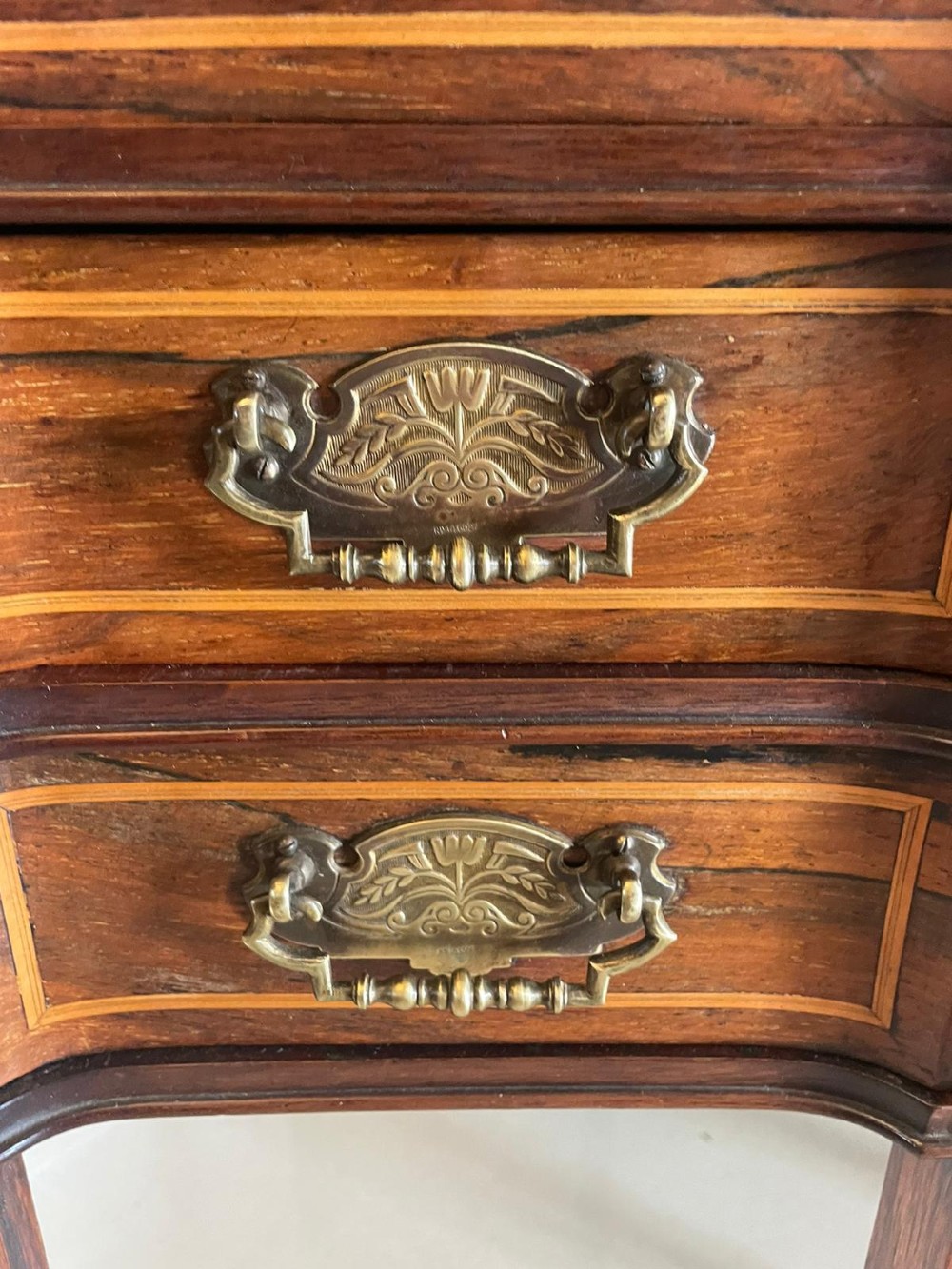 An antique Victorian inlaid writing desk with a green leather top, brass gallery railing, and multiple drawers on tapered legs with castors. View V