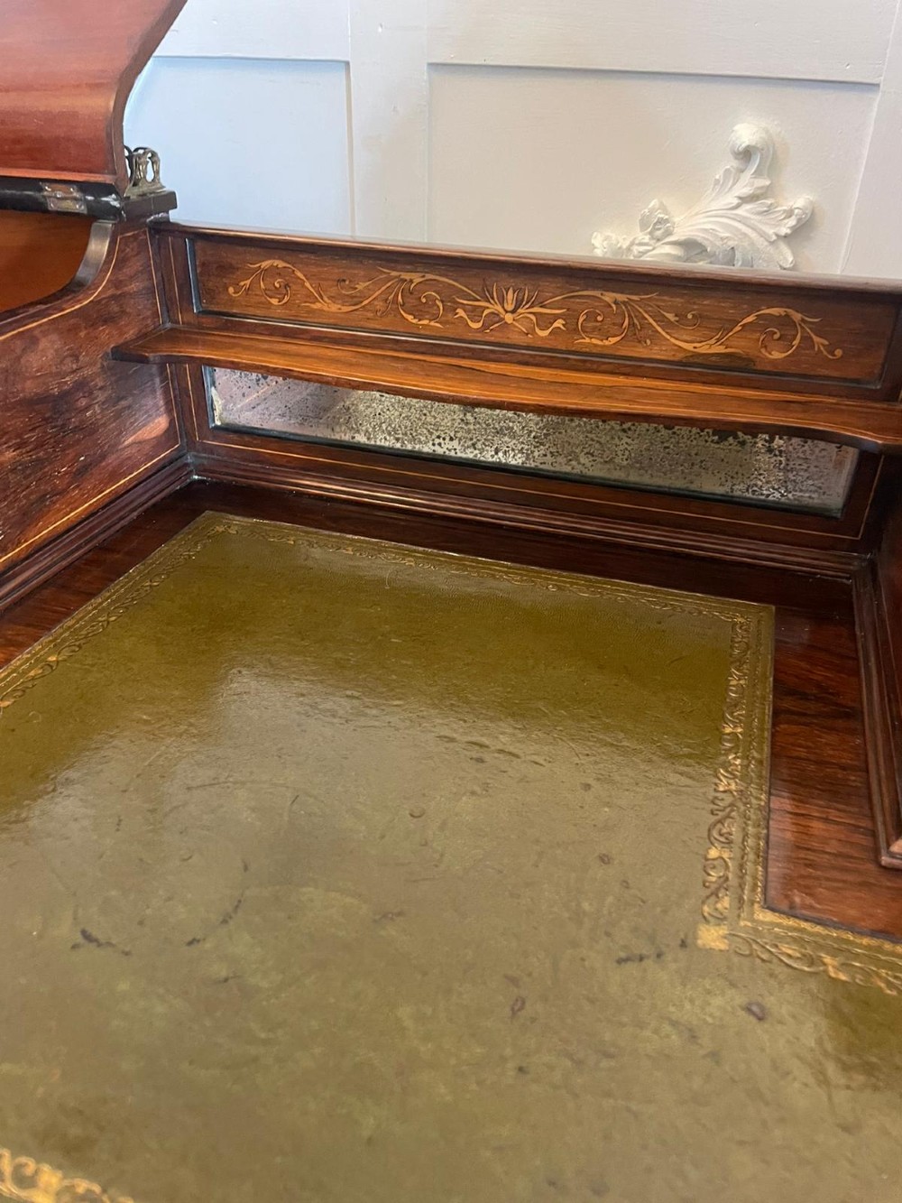 An antique Victorian inlaid writing desk with a green leather top, brass gallery railing, and multiple drawers on tapered legs with castors. View VII