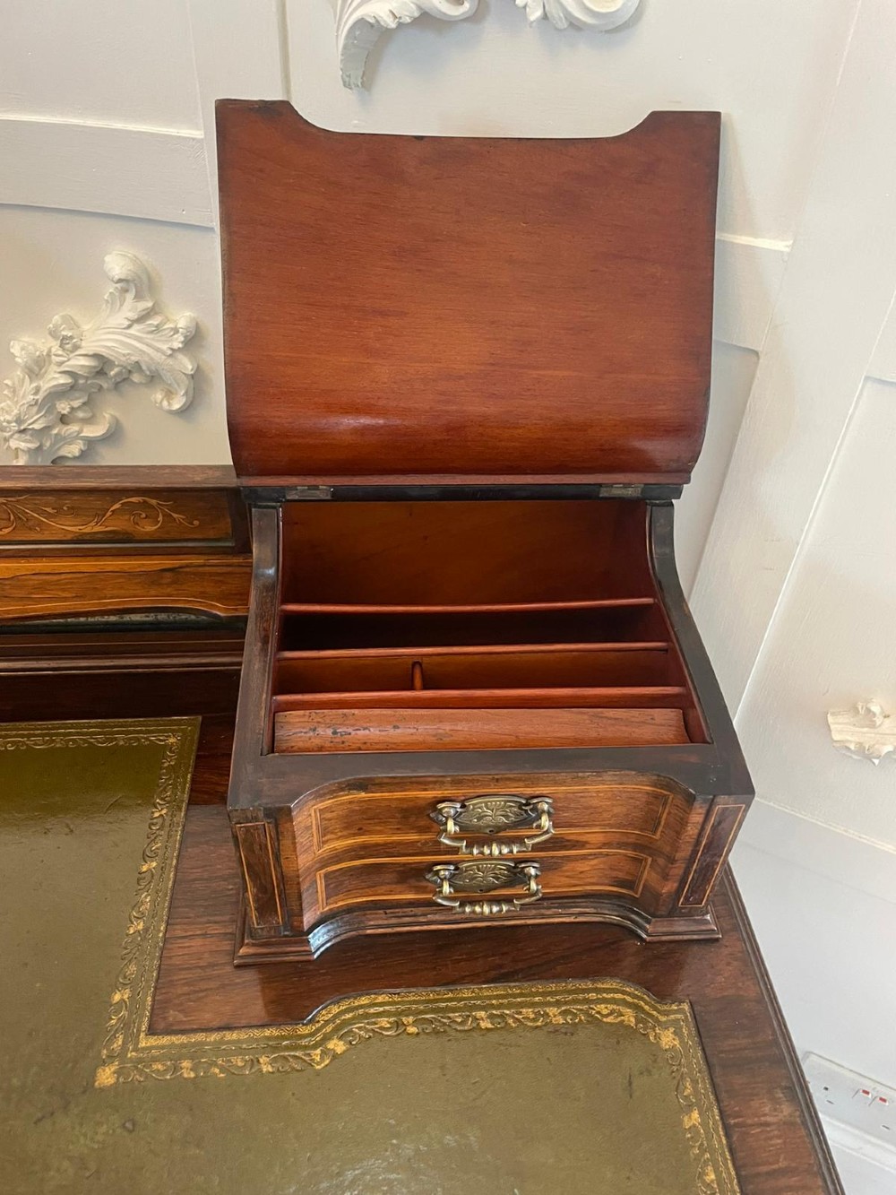 An antique Victorian inlaid writing desk with a green leather top, brass gallery railing, and multiple drawers on tapered legs with castors. View VIII