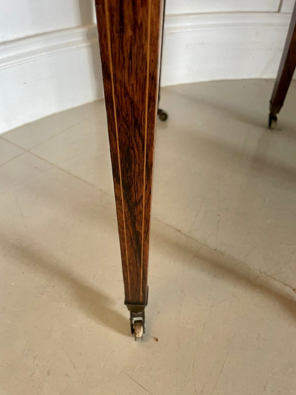 An antique Victorian inlaid writing desk with a green leather top, brass gallery railing, and multiple drawers on tapered legs with castors. View X