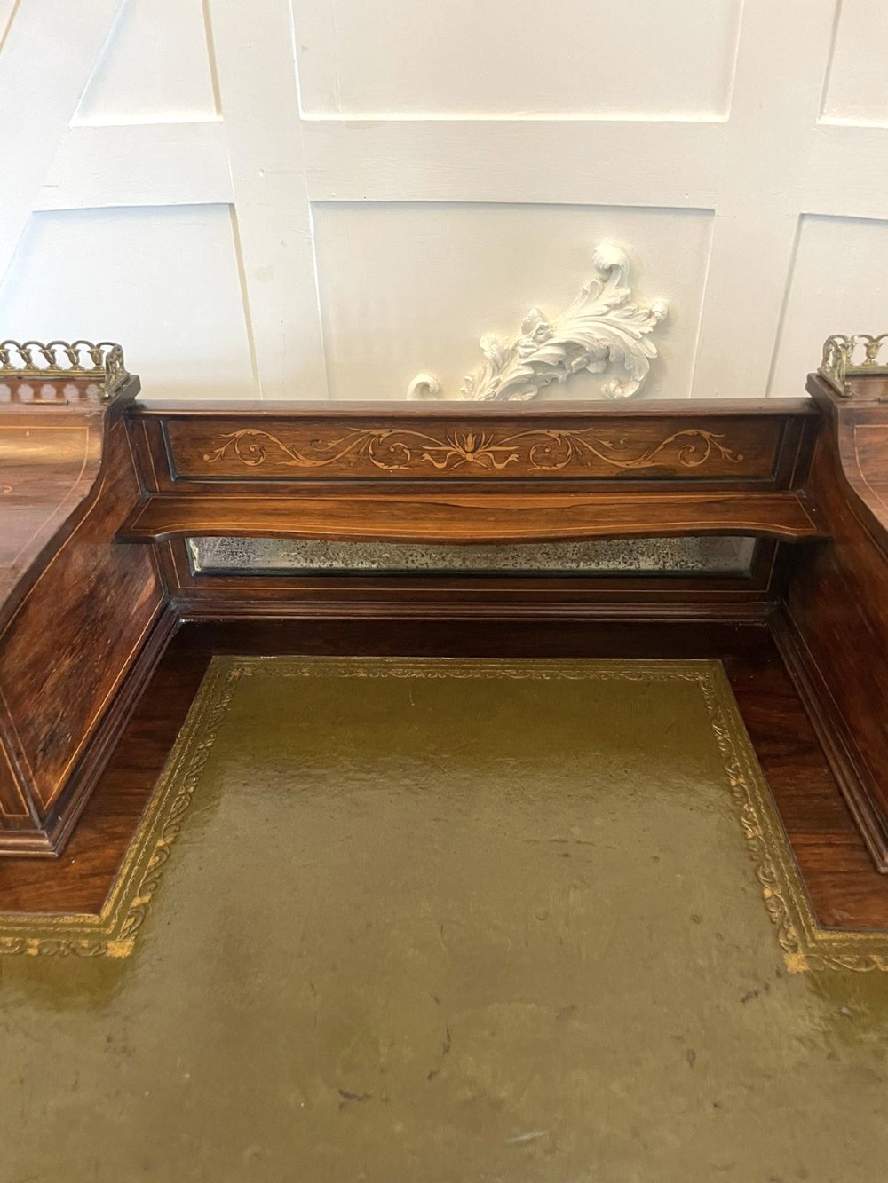 An antique Victorian inlaid writing desk with a green leather top, brass gallery railing, and multiple drawers on tapered legs with castors. View XIII