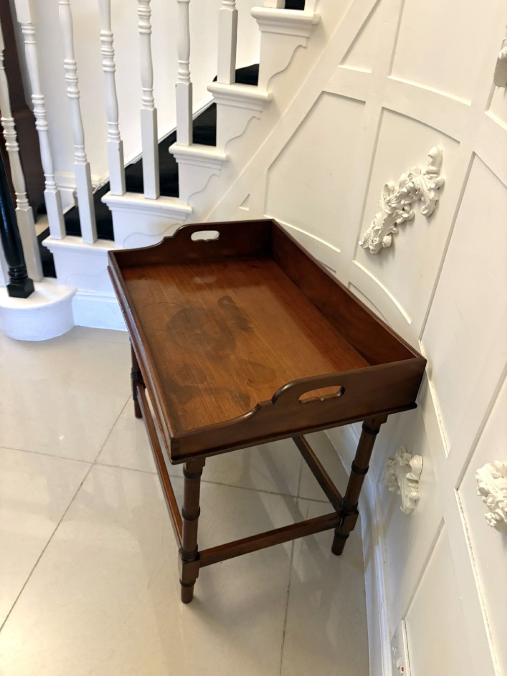 A dark mahogany tray-top occasional table featuring a raised gallery with carved carrying handles, turned legs, and stretchers. View VI