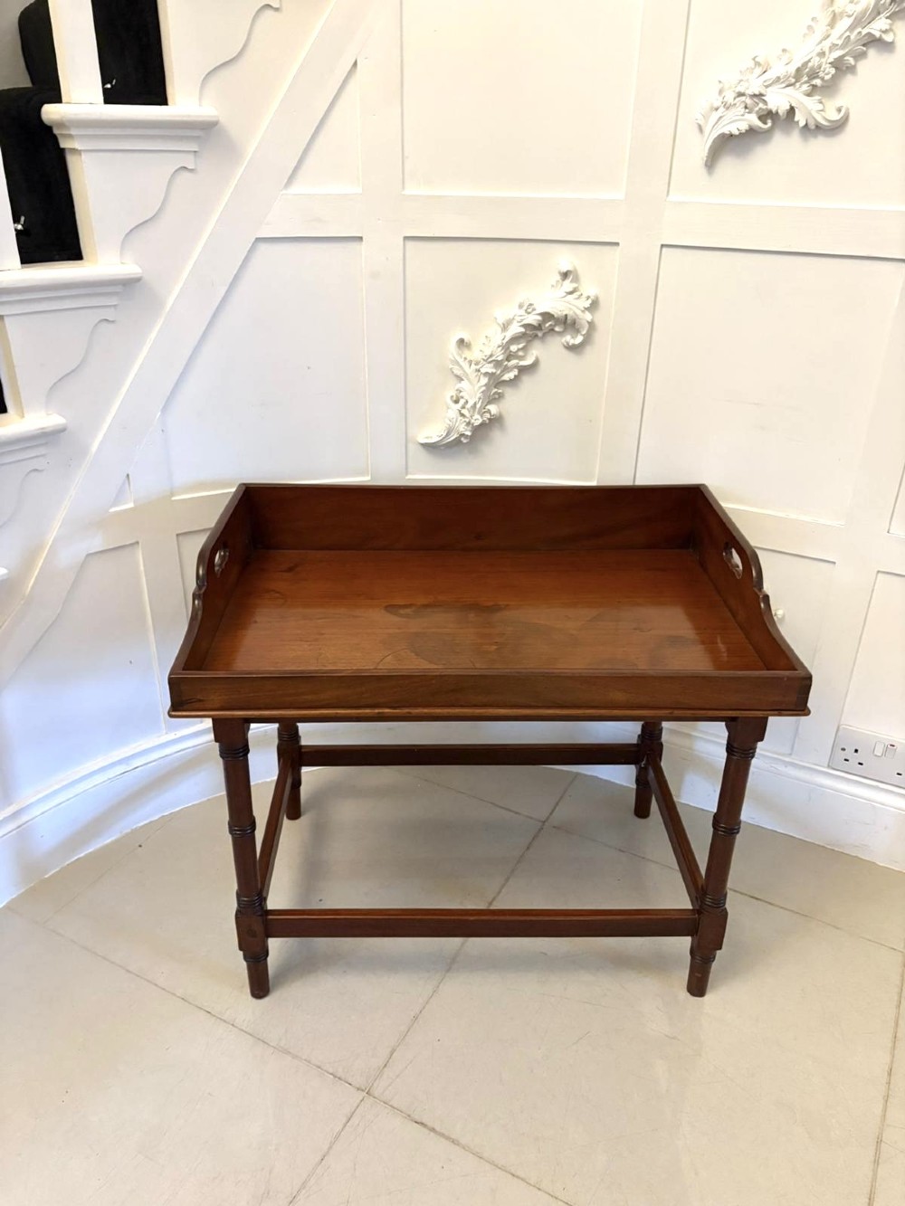 A dark mahogany tray-top occasional table featuring a raised gallery with carved carrying handles, turned legs, and stretchers. View X