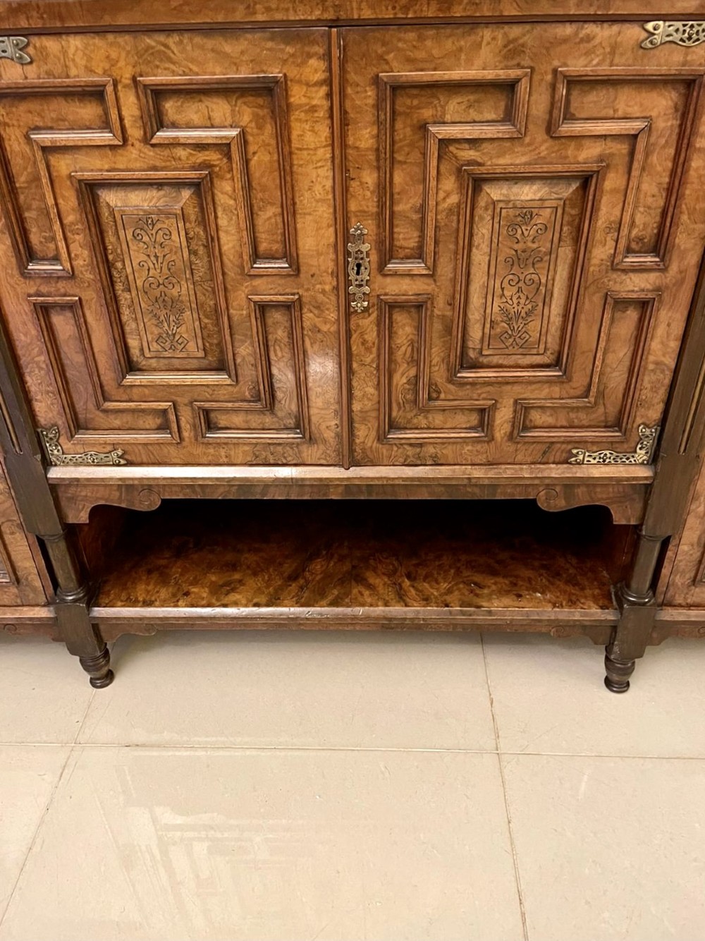 An antique Victorian burr walnut credenza featuring glazed flank doors, central geometric inlaid doors, brass fittings, and turned support columns. View III