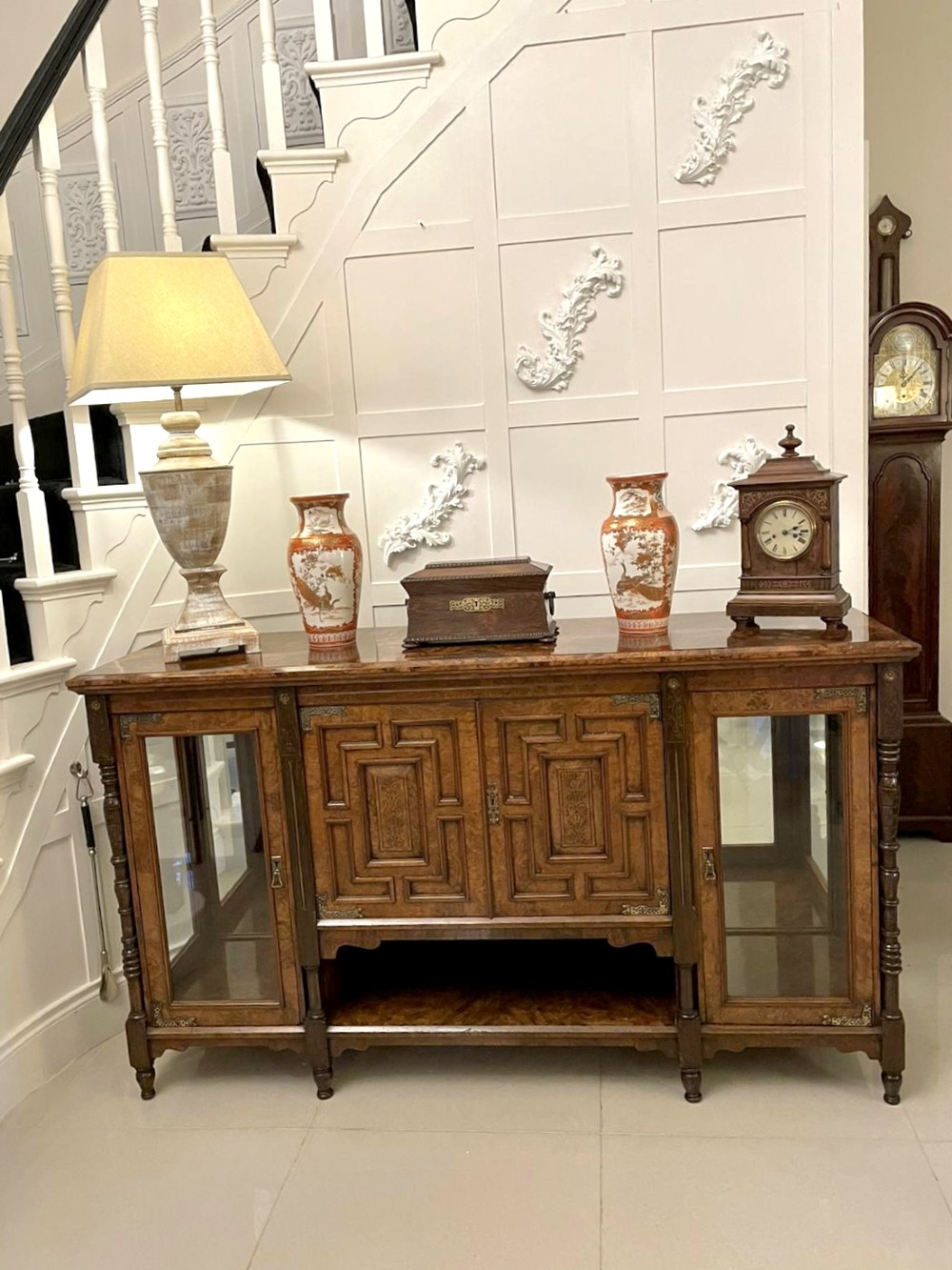 An antique Victorian burr walnut credenza featuring glazed flank doors, central geometric inlaid doors, brass fittings, and turned support columns. View V