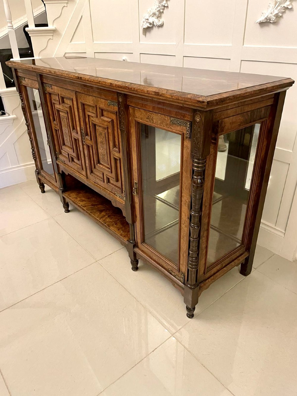 An antique Victorian burr walnut credenza featuring glazed flank doors, central geometric inlaid doors, brass fittings, and turned support columns. View VI
