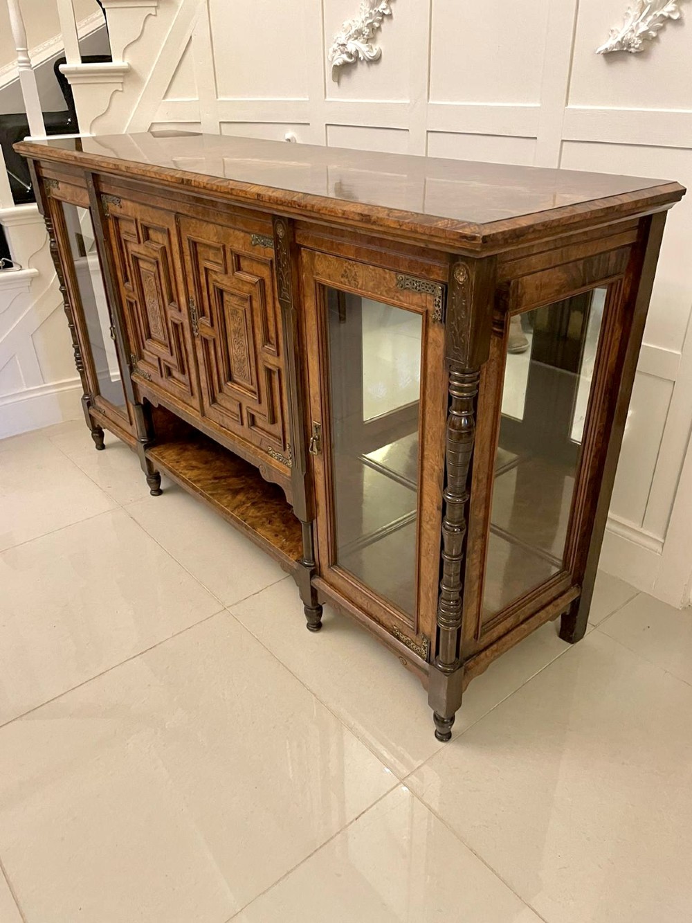 An antique Victorian burr walnut credenza featuring glazed flank doors, central geometric inlaid doors, brass fittings, and turned support columns. View VII