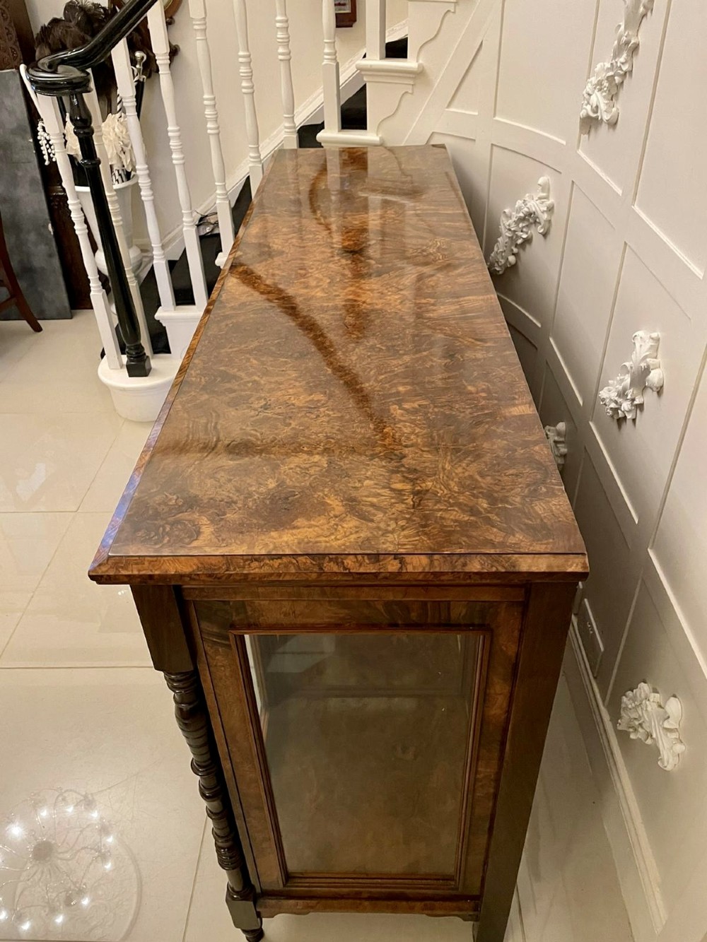 An antique Victorian burr walnut credenza featuring glazed flank doors, central geometric inlaid doors, brass fittings, and turned support columns. View IX