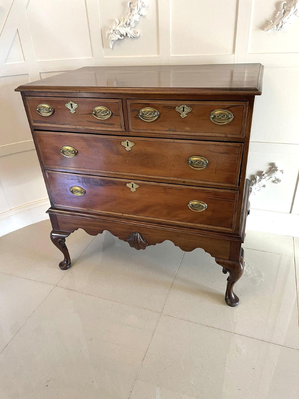 A George III mahogany chest on stand featuring two short over two long drawers, brass handles, a carved shell apron, and cabriole legs. View II