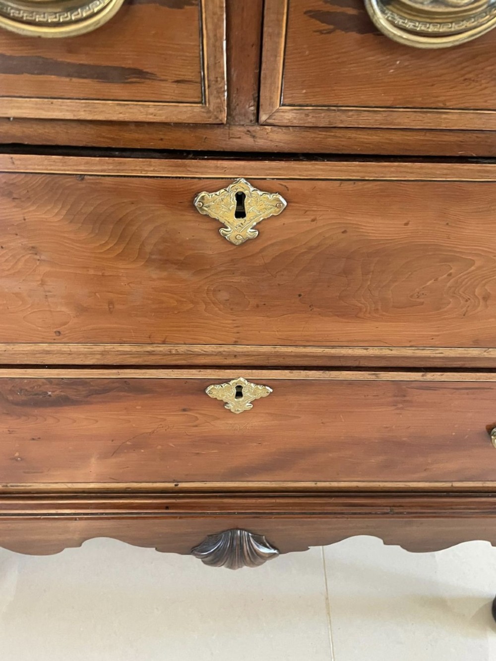 A George III mahogany chest on stand featuring two short over two long drawers, brass handles, a carved shell apron, and cabriole legs. View III