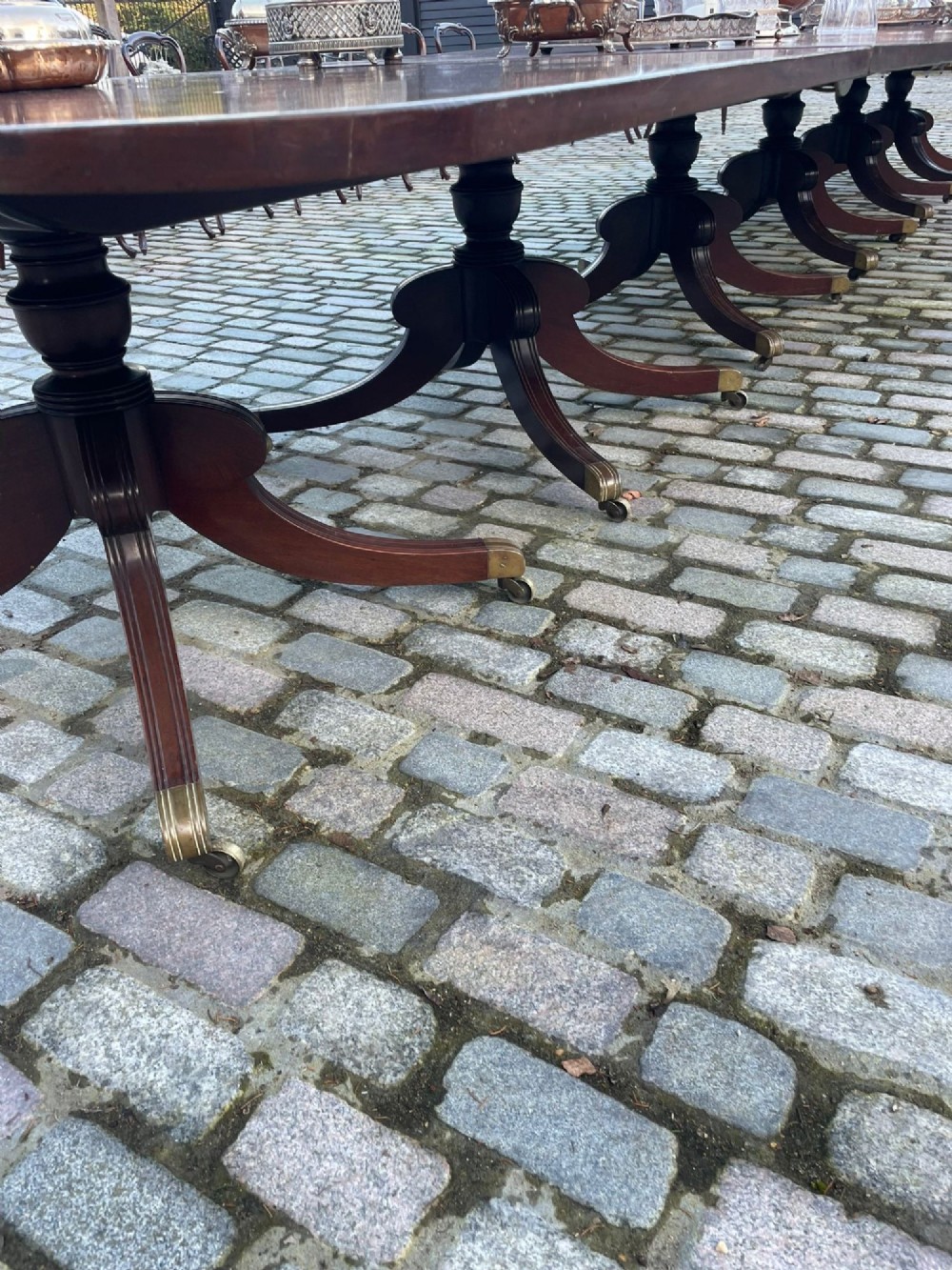 A long George III mahogany extending dining table with multiple pedestal bases resting on splayed reeded legs with brass castors. View V