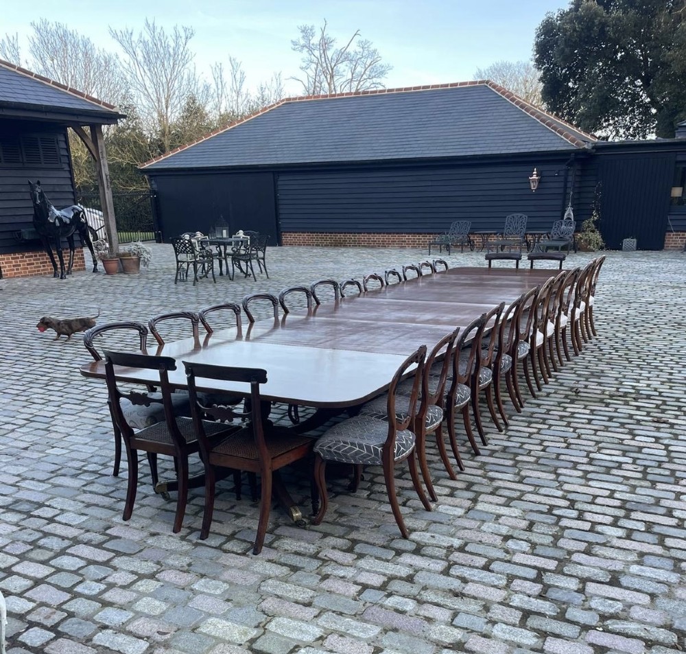 A long George III mahogany extending dining table with multiple pedestal bases resting on splayed reeded legs with brass castors. View VIII