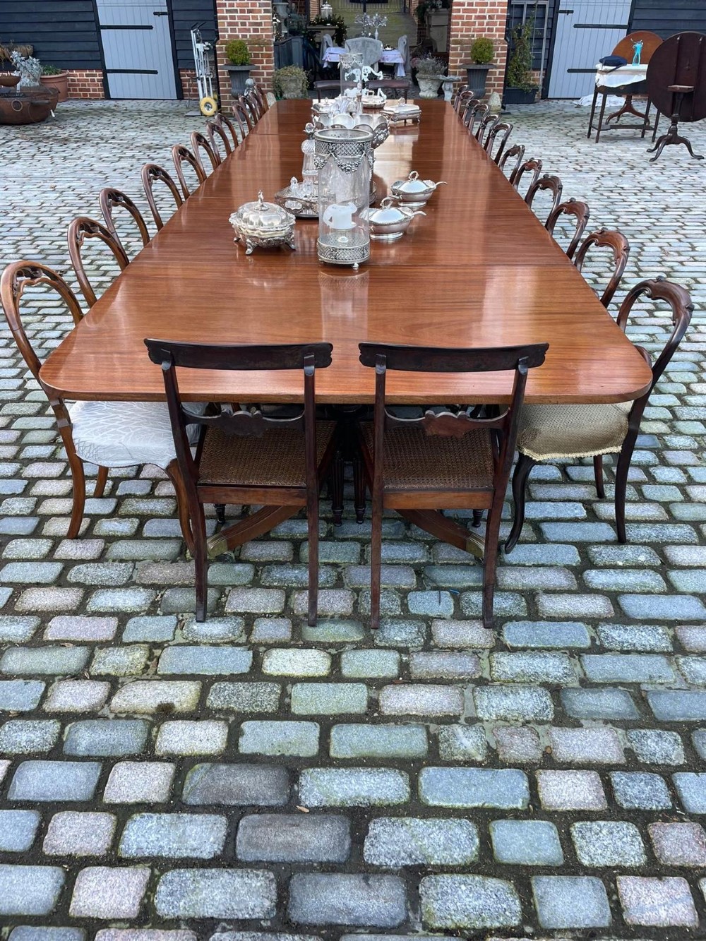 A long George III mahogany extending dining table with multiple pedestal bases resting on splayed reeded legs with brass castors. View IX
