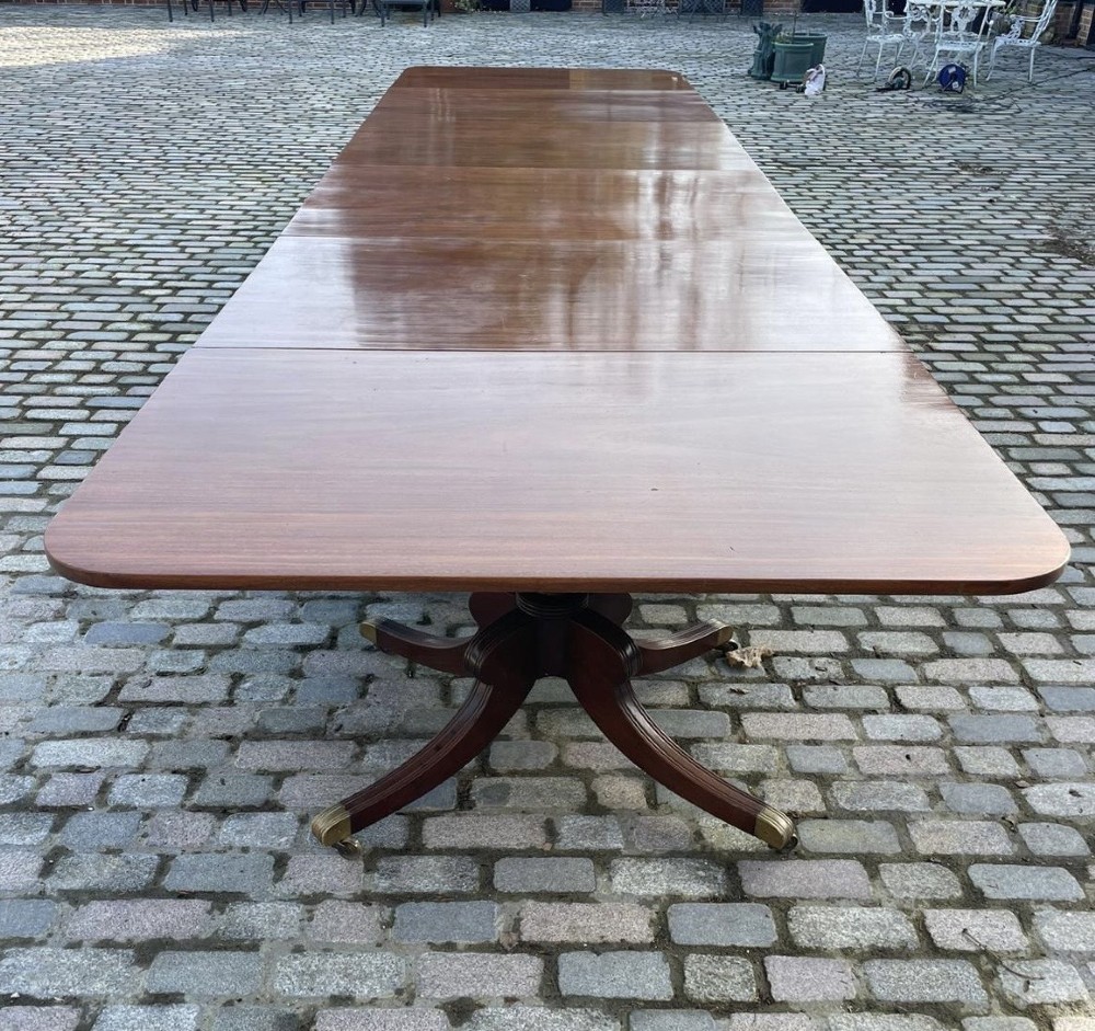 A long George III mahogany extending dining table with multiple pedestal bases resting on splayed reeded legs with brass castors.