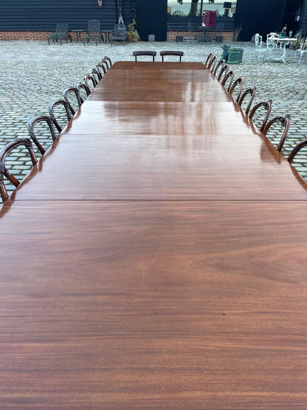A long George III mahogany extending dining table with multiple pedestal bases resting on splayed reeded legs with brass castors. View XI