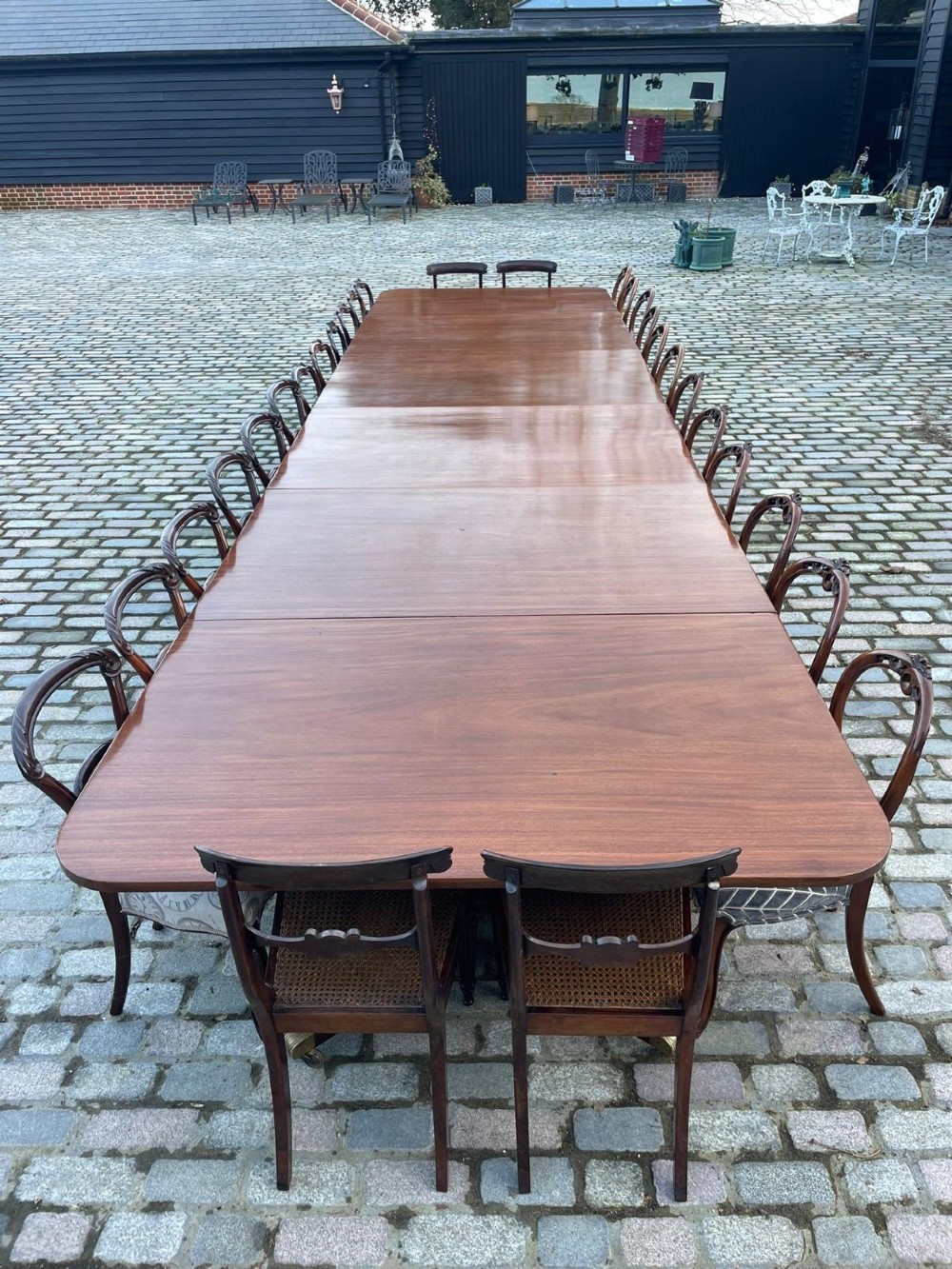 A long George III mahogany extending dining table with multiple pedestal bases resting on splayed reeded legs with brass castors. View XII