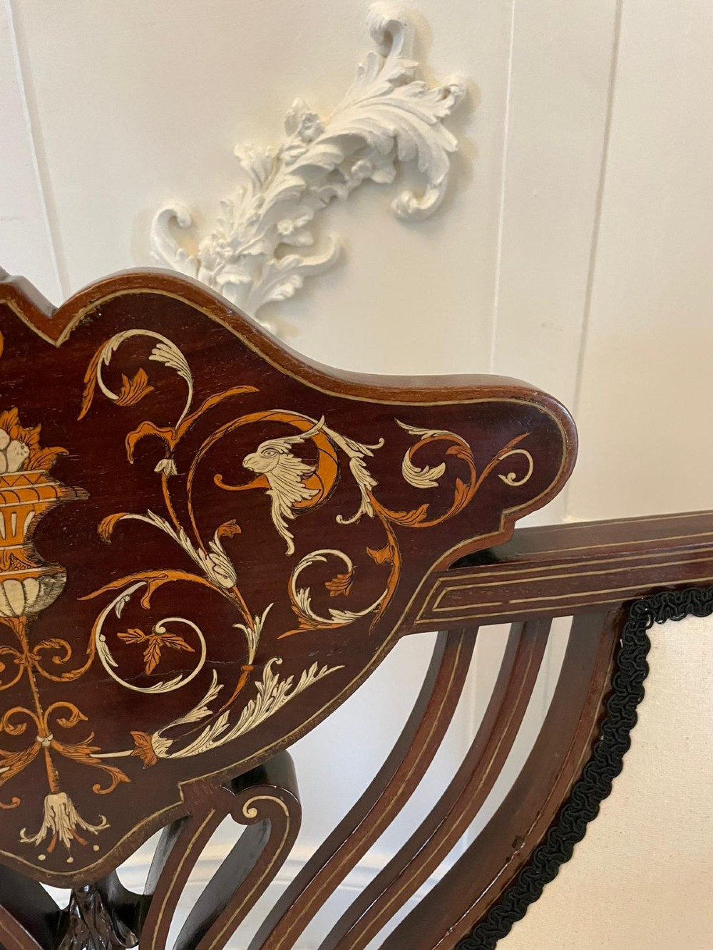 An antique Victorian mahogany settee featuring cream upholstered seating, curved arms, cabriole legs, and a central back splat with intricate floral wood inlay. View V