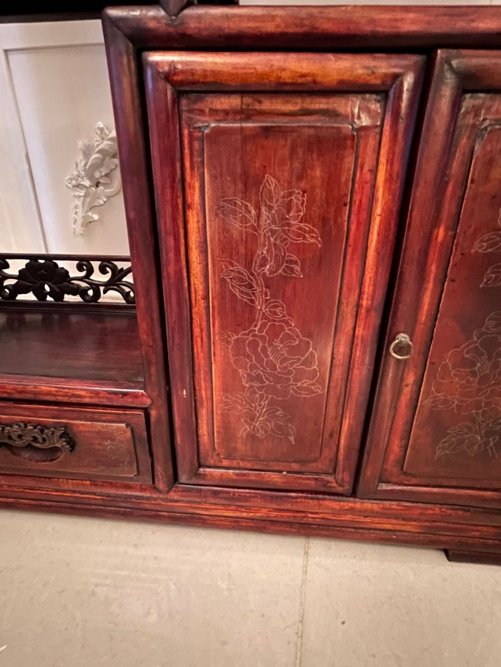 An antique dark reddish-brown Chinese hardwood display cabinet featuring asymmetrical open shelves, carved scrollwork galleries, and two small cupboards. View II