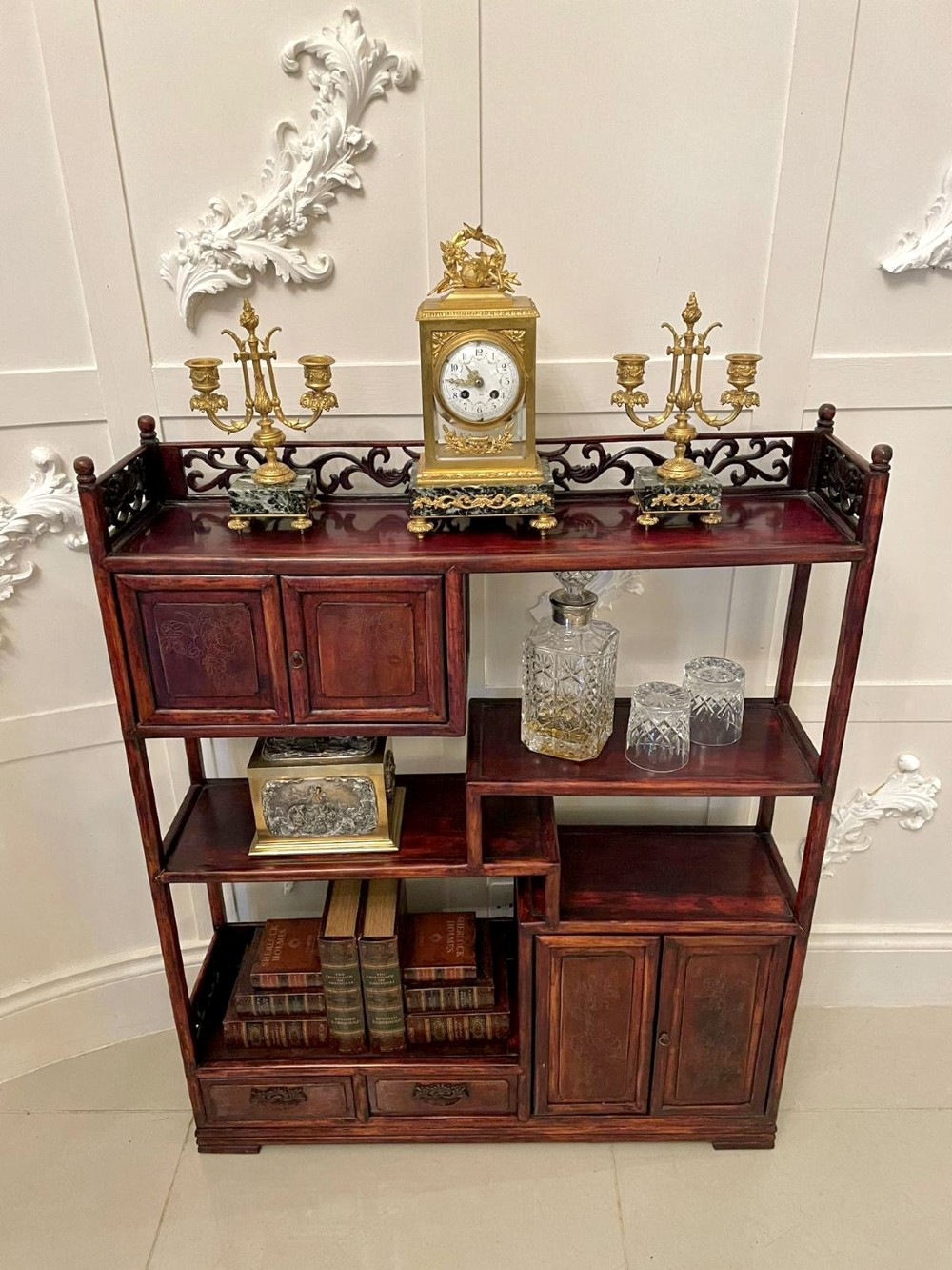 An antique dark reddish-brown Chinese hardwood display cabinet featuring asymmetrical open shelves, carved scrollwork galleries, and two small cupboards. View V