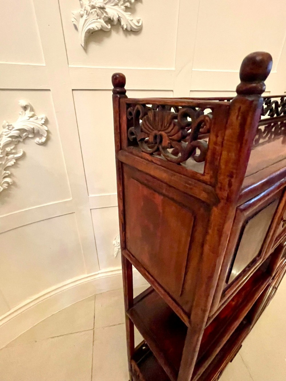 An antique dark reddish-brown Chinese hardwood display cabinet featuring asymmetrical open shelves, carved scrollwork galleries, and two small cupboards. View IX