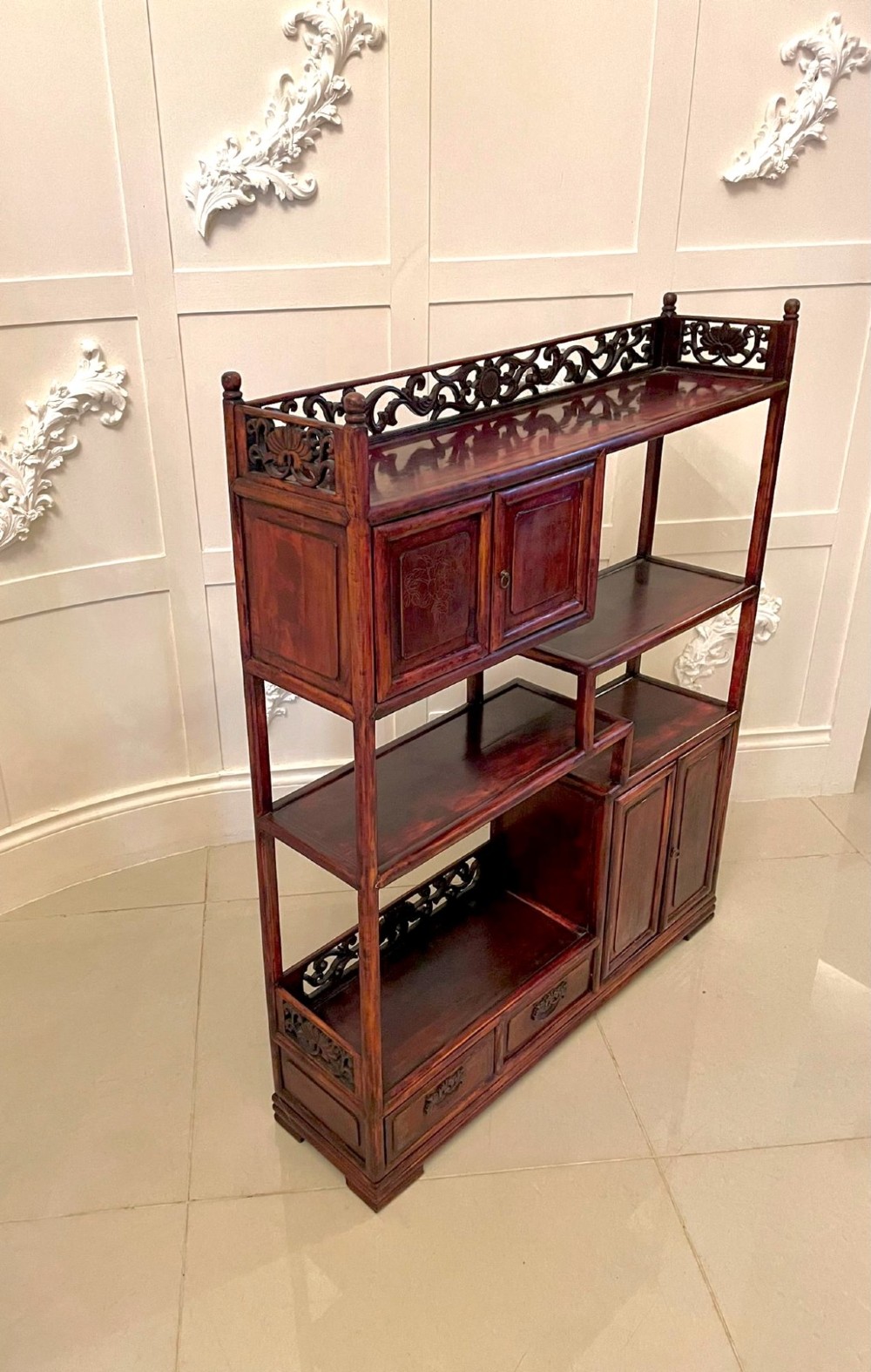 An antique dark reddish-brown Chinese hardwood display cabinet featuring asymmetrical open shelves, carved scrollwork galleries, and two small cupboards. View X