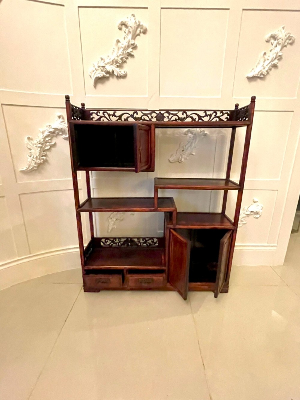An antique dark reddish-brown Chinese hardwood display cabinet featuring asymmetrical open shelves, carved scrollwork galleries, and two small cupboards. View XI