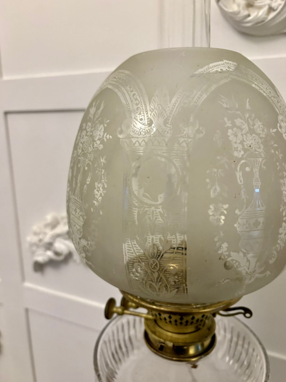 A tall Victorian oil lamp featuring a pink porcelain body with blue floral trellis decoration, a cast brass base, a cut glass reservoir, and an etched glass shade. View IX