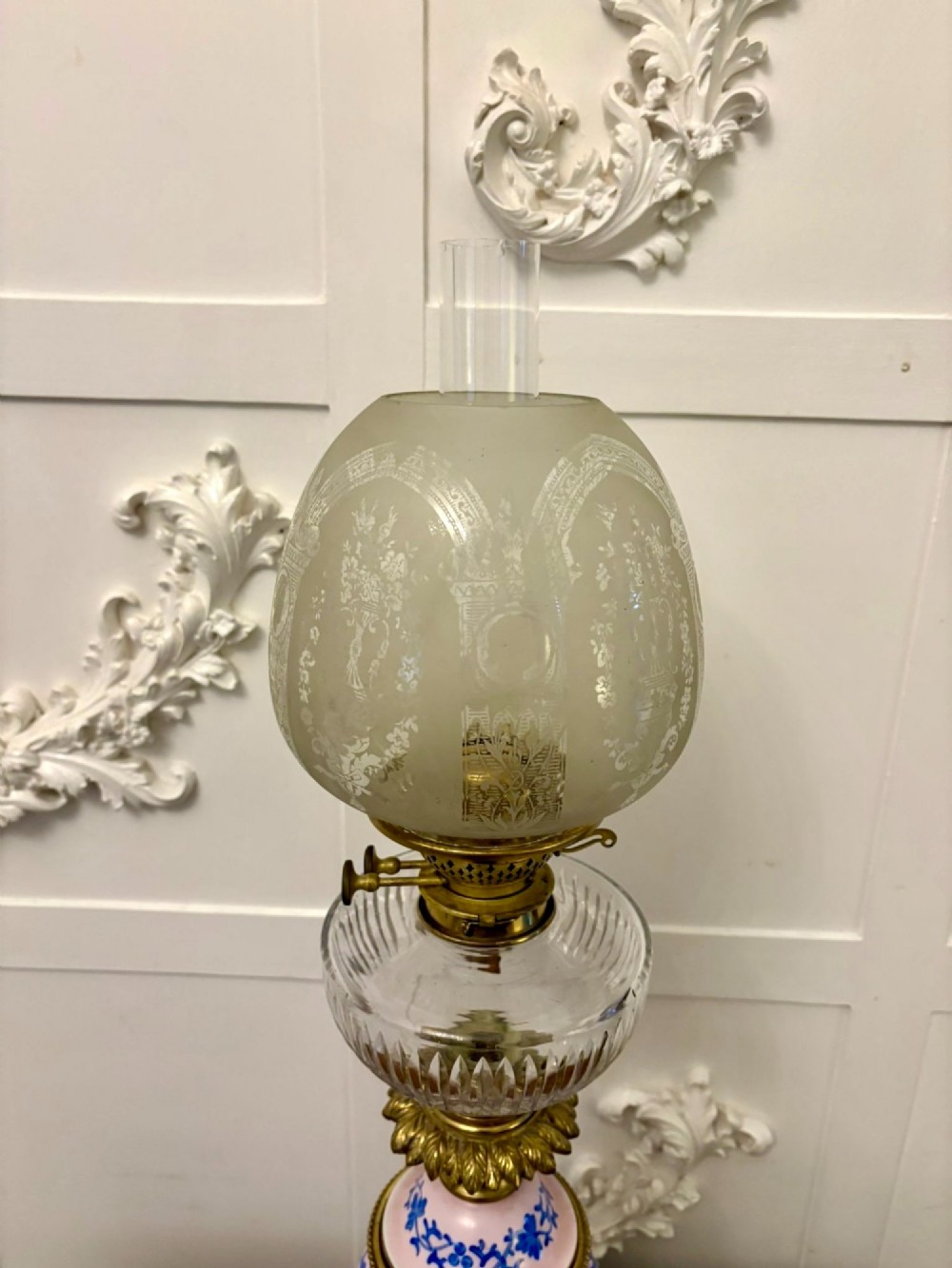 A tall Victorian oil lamp featuring a pink porcelain body with blue floral trellis decoration, a cast brass base, a cut glass reservoir, and an etched glass shade. View XI