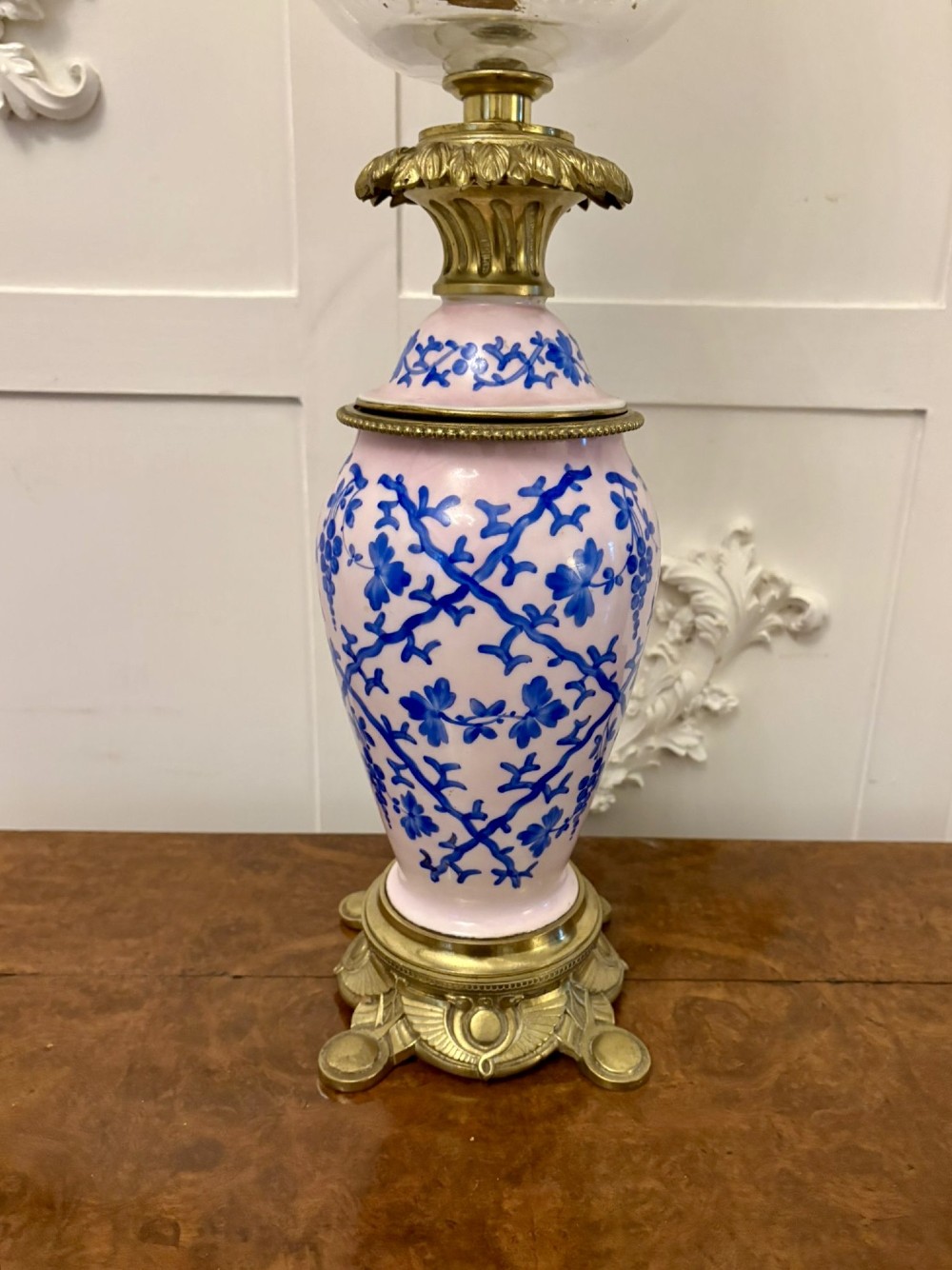 A tall Victorian oil lamp featuring a pink porcelain body with blue floral trellis decoration, a cast brass base, a cut glass reservoir, and an etched glass shade. View XII