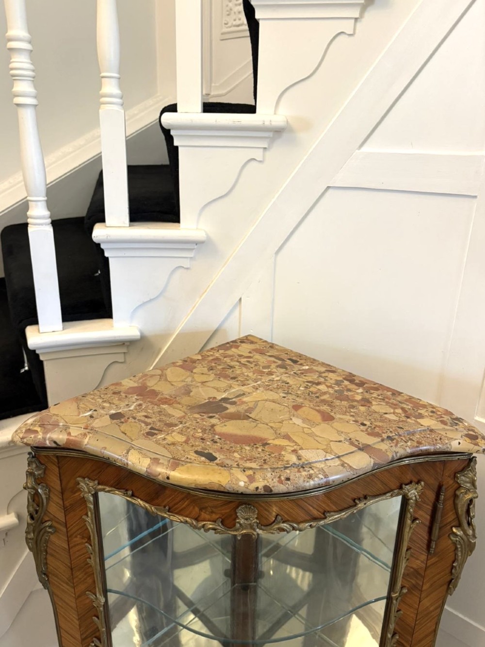 An antique French serpentine corner display cabinet crafted from kingwood with a marble top, curved glass door, internal glass shelves, and gilded ormolu mounts. View V
