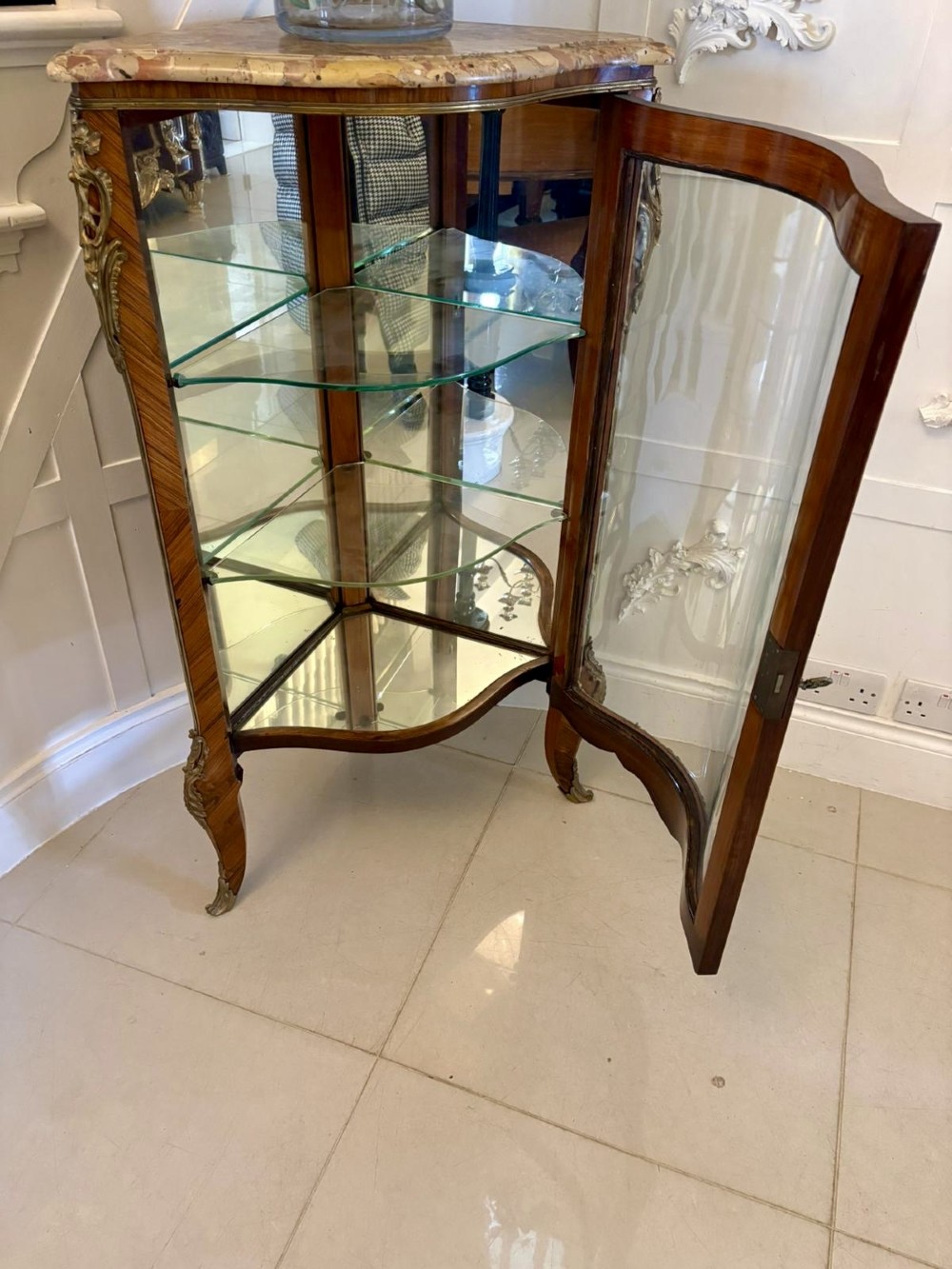 An antique French serpentine corner display cabinet crafted from kingwood with a marble top, curved glass door, internal glass shelves, and gilded ormolu mounts. View VIII